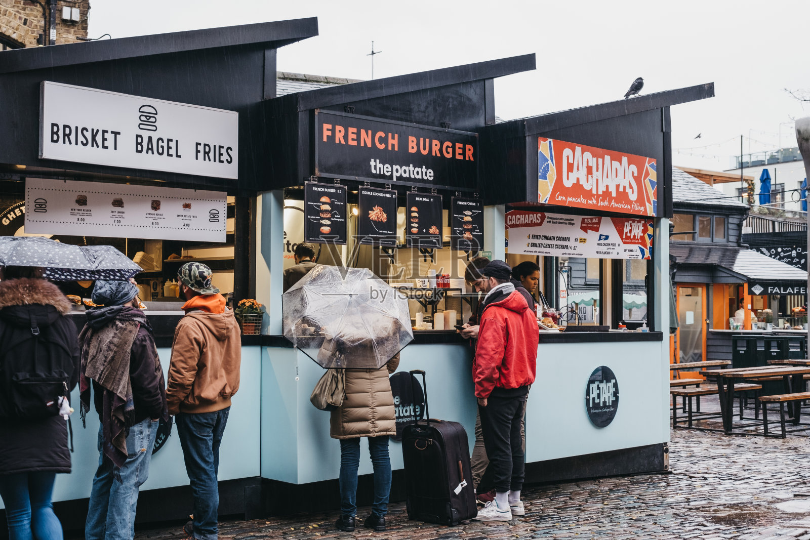 在英国伦敦卡姆登市场内，人们在雨中从不同摊位订购食物照片摄影图片