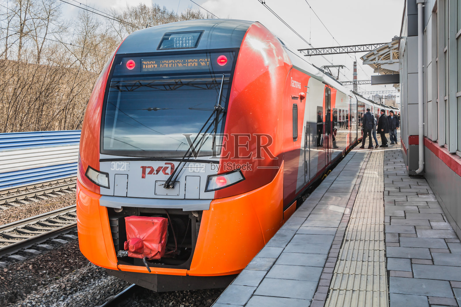 新的红色和橙色的电动火车Lastochka已经在春天抵达俄罗斯铁路的一个新火车站照片摄影图片