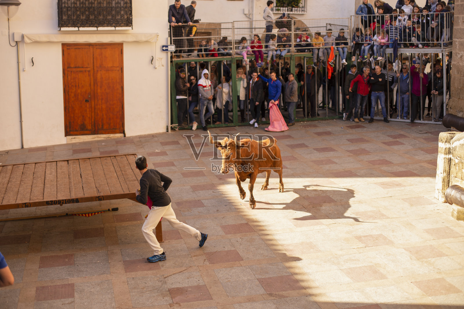 在圣塞巴斯蒂安的庆祝活动中，在居民和游客面前，一头公牛在街上追赶一个人。照片摄影图片