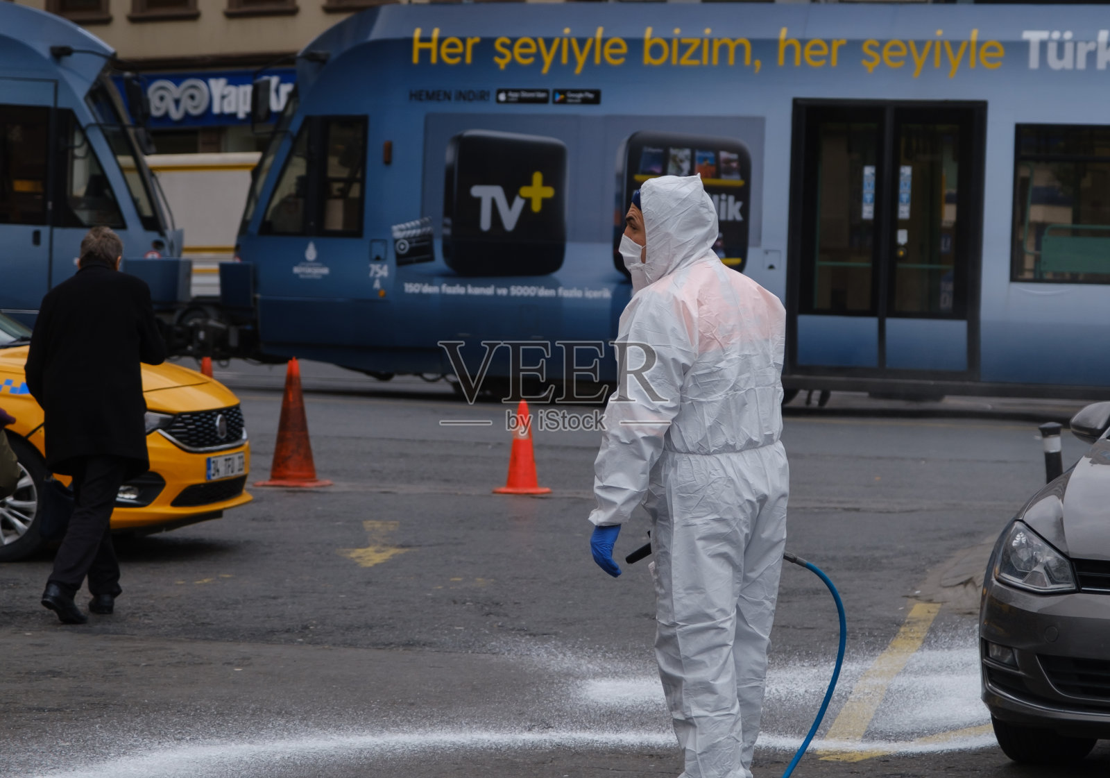 伊斯坦布尔一名男子戴着口罩，穿着防护装备，正在进行街道清洁消毒。病毒大流行照片摄影图片