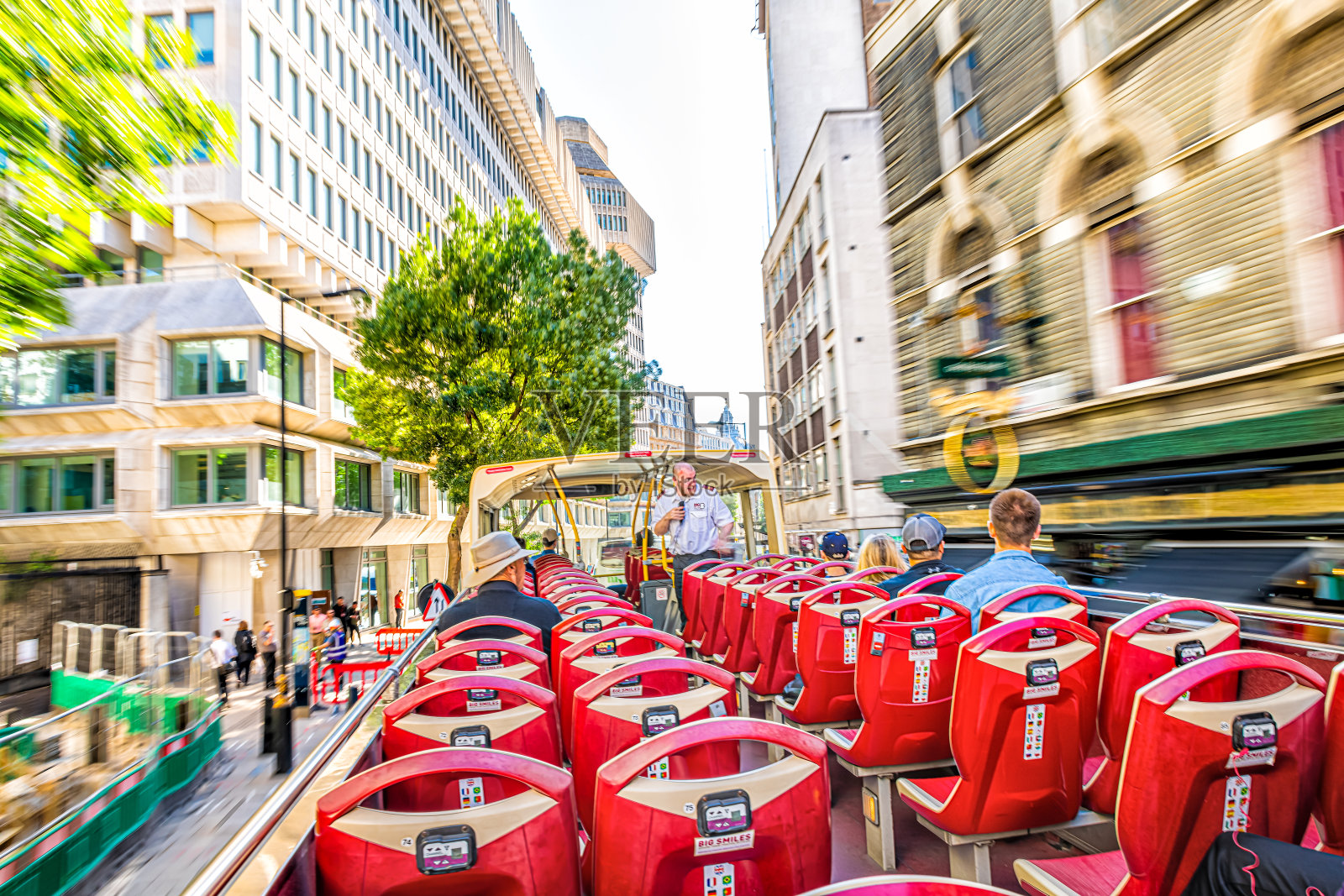红色双层大巴士带着导游和游客驾车模糊的导游照片摄影图片