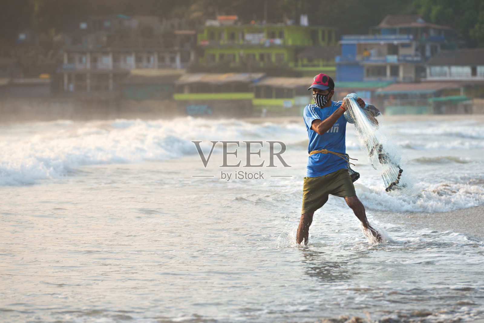 2020年4月3日印度，GOA, Arambol，渔民戴着防护口罩在海边捕鱼，以防止COVID-19冠状病毒在印度的21天隔离期间传播，封锁和宵禁的概念照片摄影图片