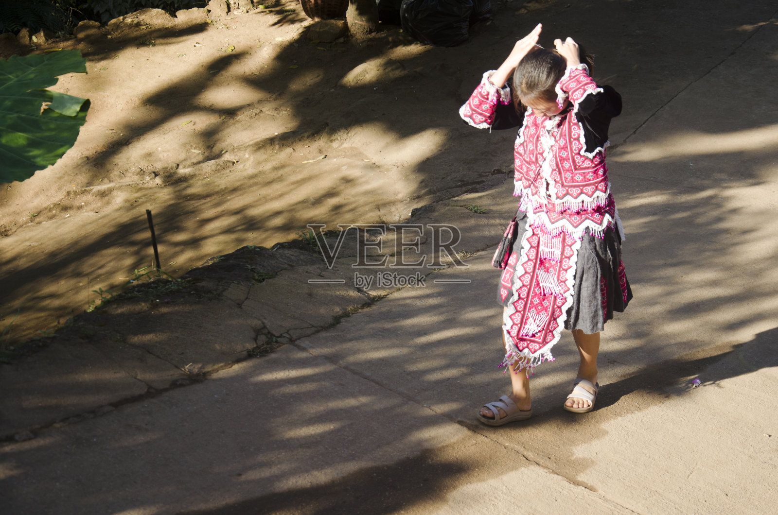 苗族女童身着传统服装，走着路照片摄影图片
