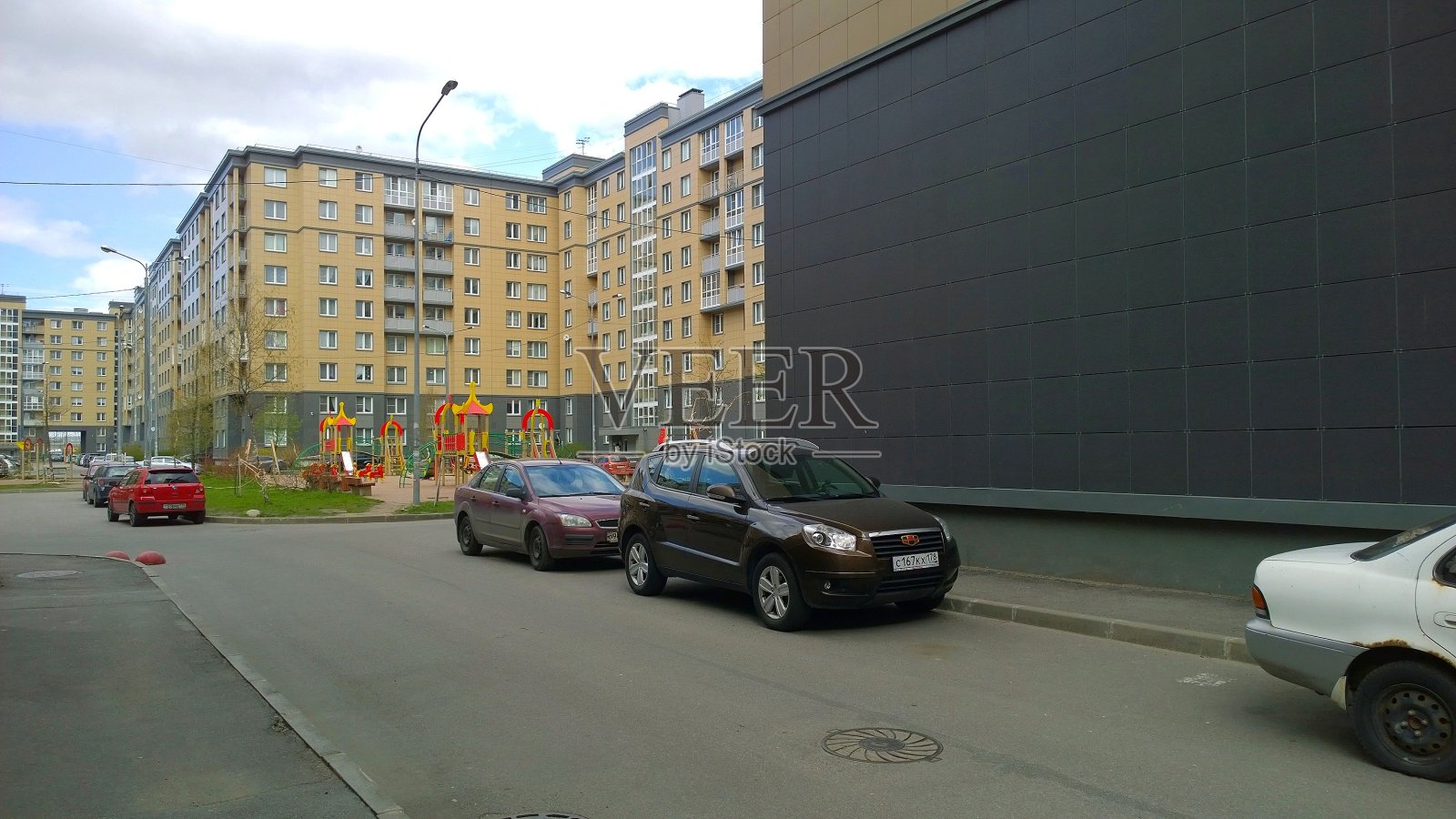 新的多层住宅区。销售和出租经济舱公寓和舒适住房。在建筑物附近停放的汽车。城市景观。城市生活。生活照片摄影图片