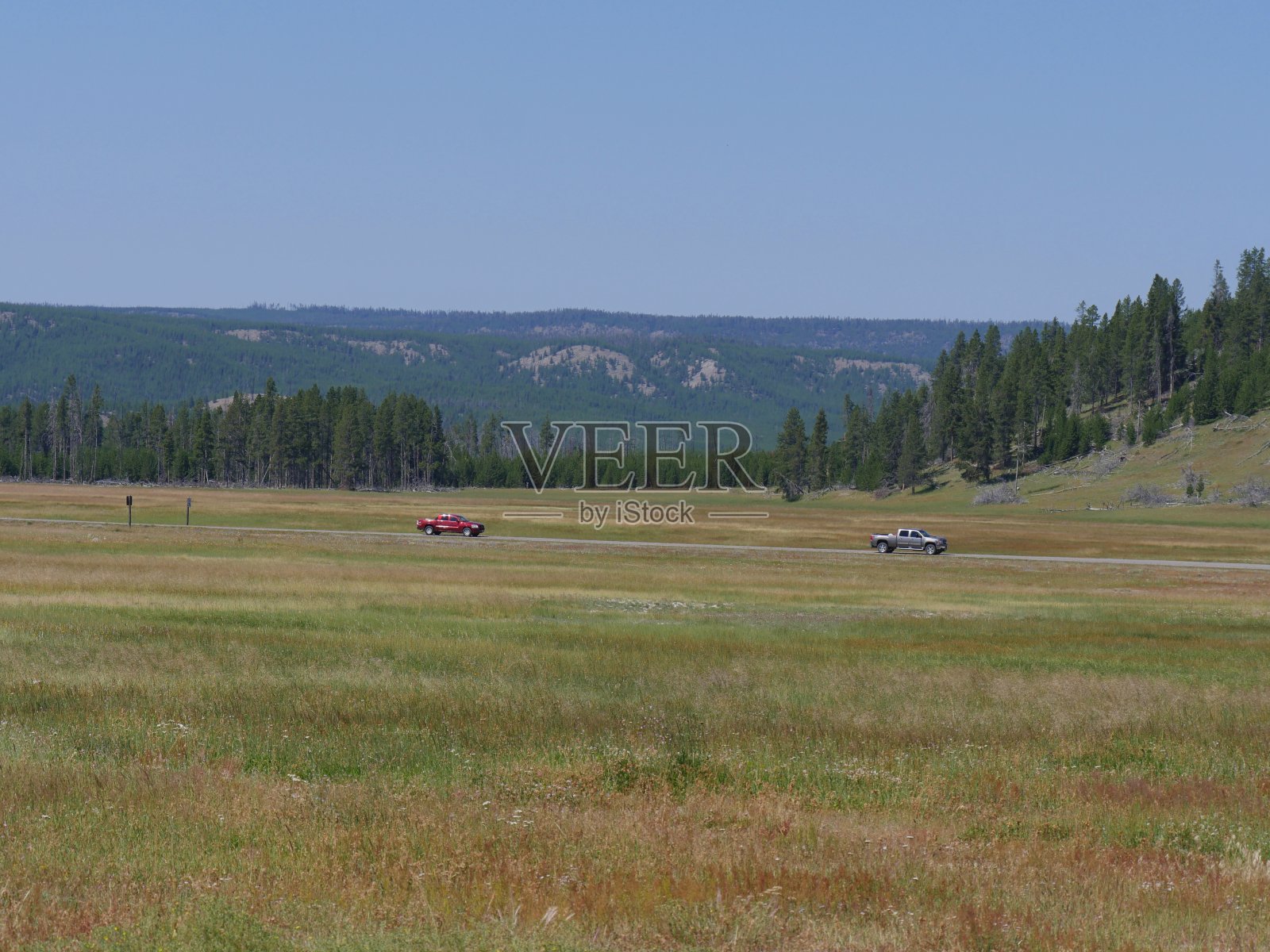 风景秀丽的黄石国家公园，有两辆车行驶在路上。照片摄影图片