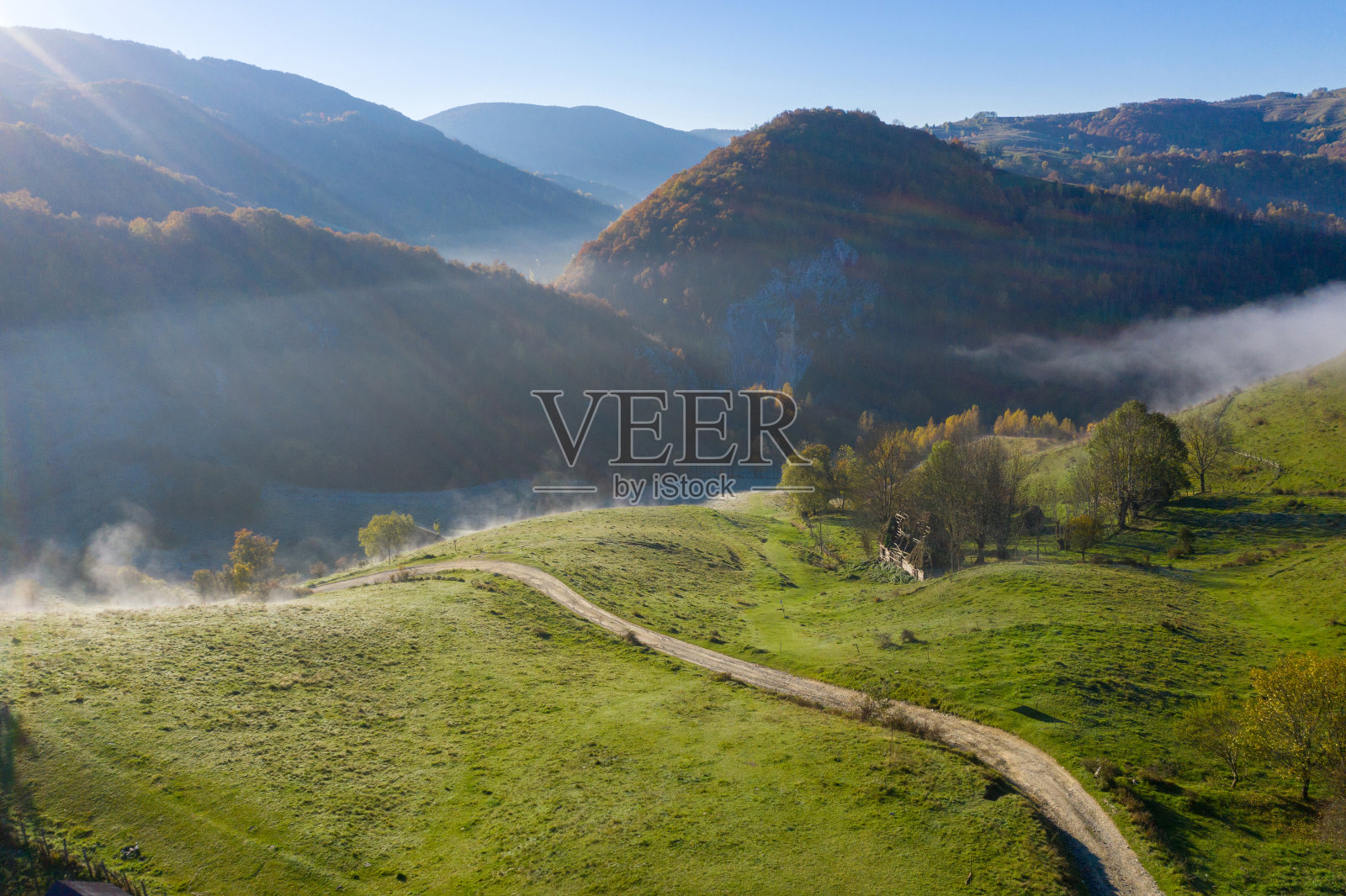 清晨的薄雾笼罩着群山。空中无人机拍摄的秋季乡村丘陵照片摄影图片