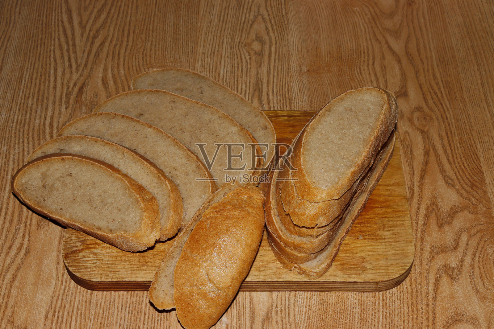 一块面包被切成片放在厨房板上的画面。照片摄影图片