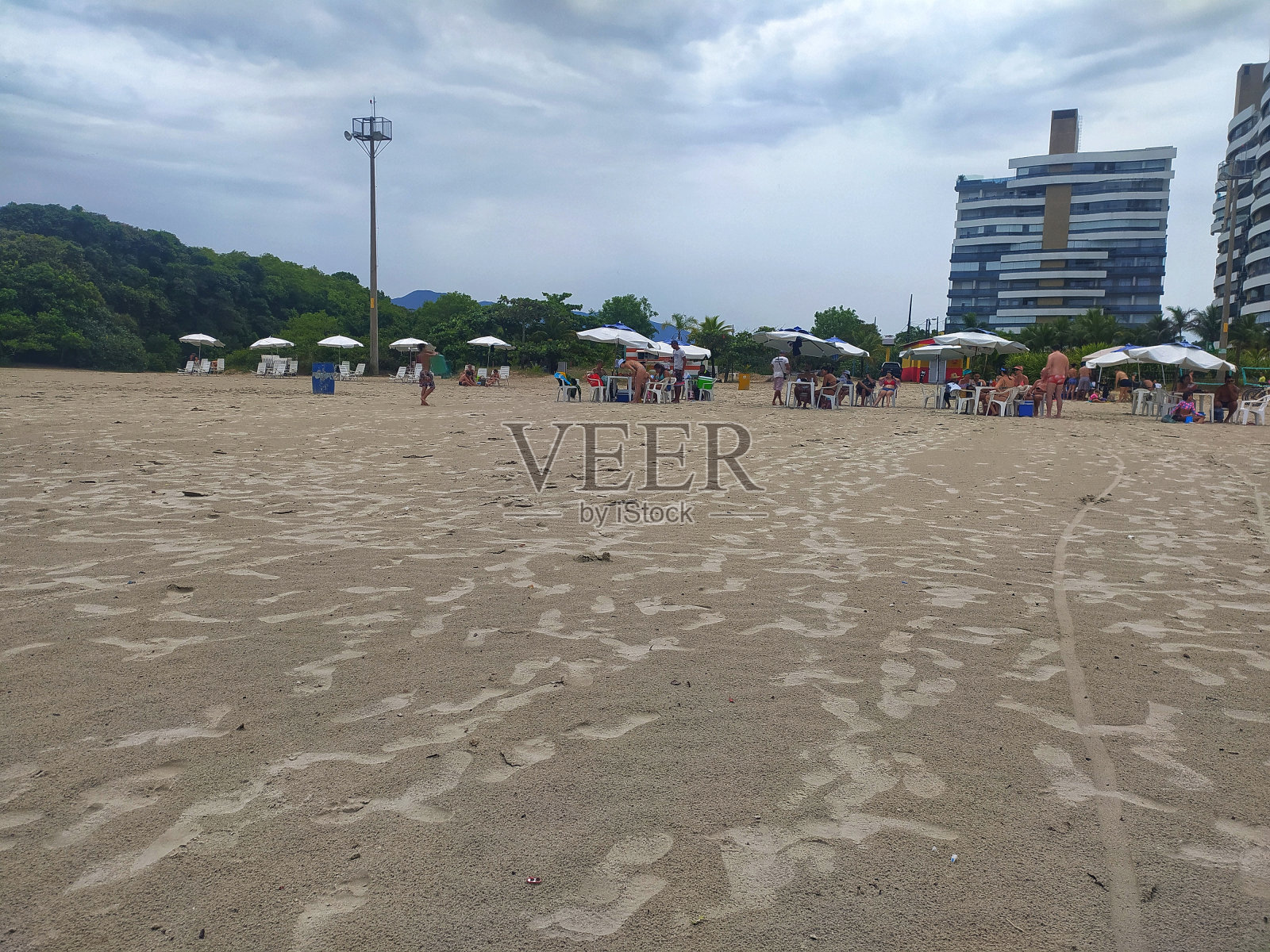 清晨，一些游客打着阳伞，坐在折叠椅上享受圣洛伦哥海滩照片摄影图片