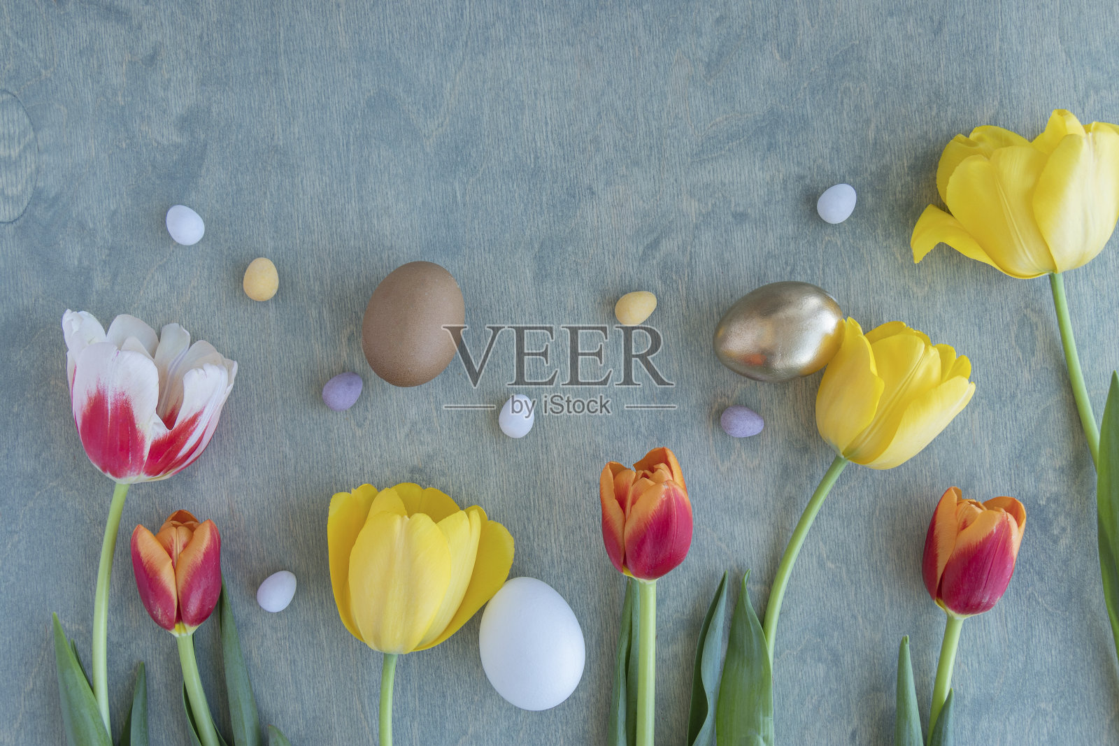 复活节背景黄色，红色郁金香和巧克力蛋在一个木制的绿色背景与文本空间。复制空间，俯视图，平躺，复活节快乐照片摄影图片