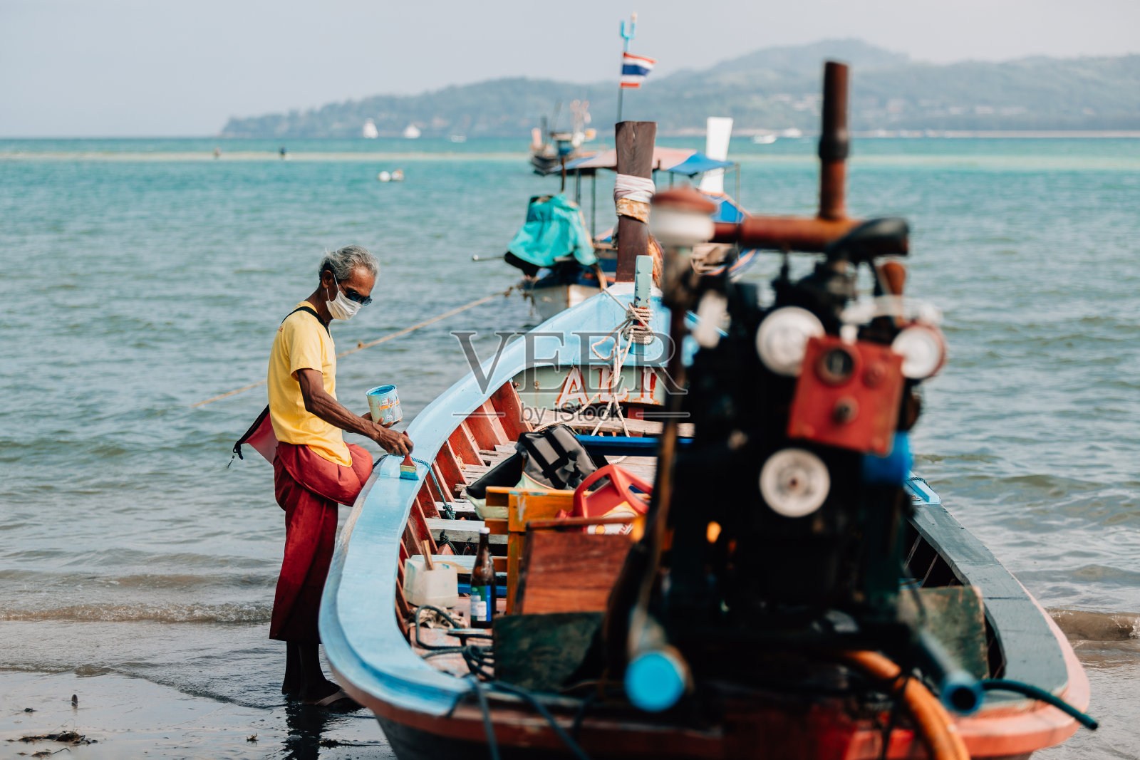 当地渔民正在给长尾船重新上色。照片摄影图片
