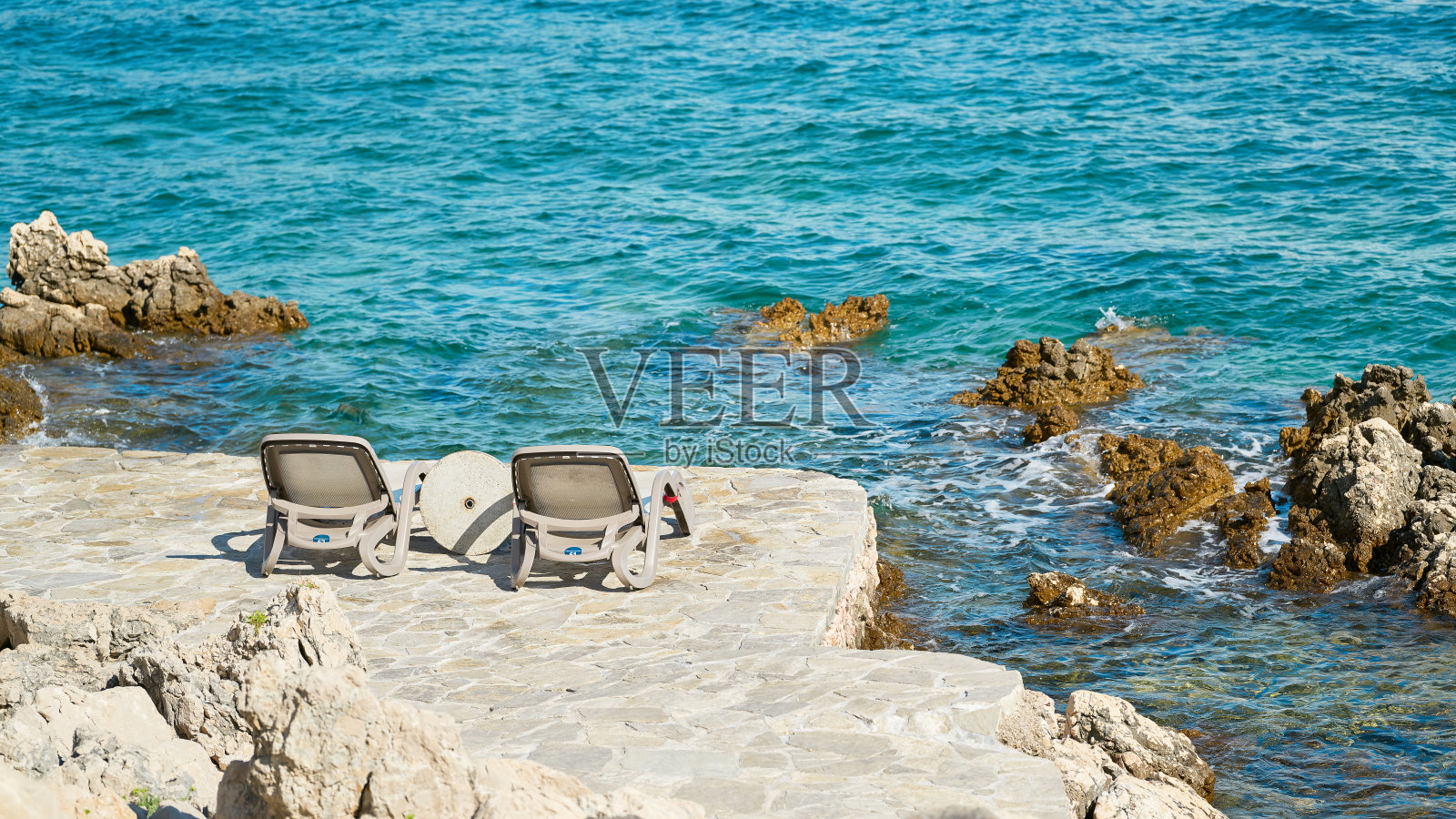 在克罗地亚Krk附近岩石海岸的一个浴场有两个日光浴床照片摄影图片