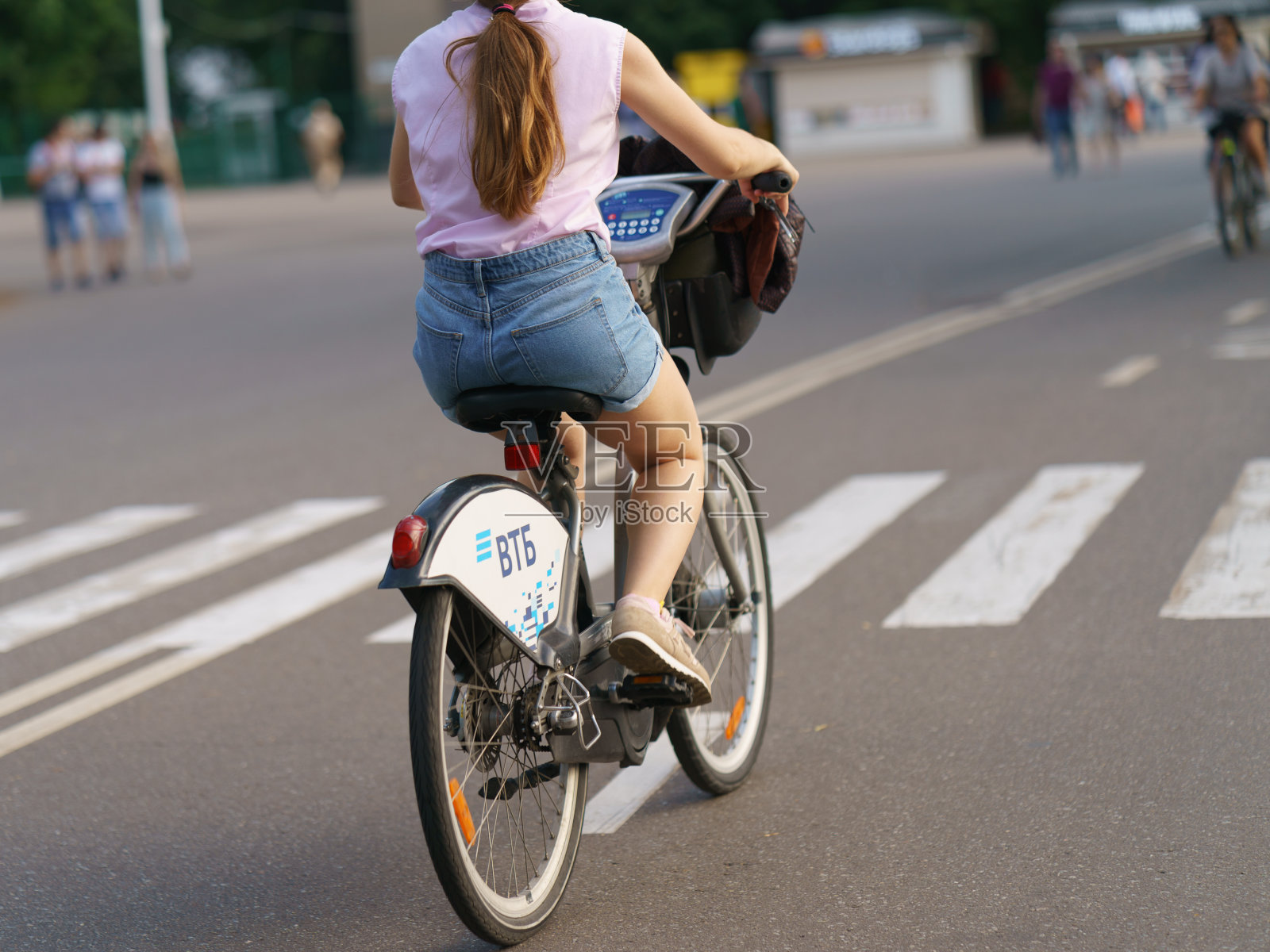 一个年轻女子在炎热的夏天在公园里骑自行车照片摄影图片