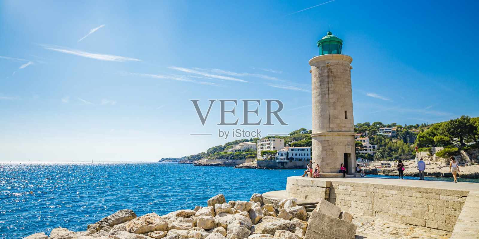 卡西斯灯塔在港口和岩石海滨，一些游客在法国普罗旺斯参观照片摄影图片