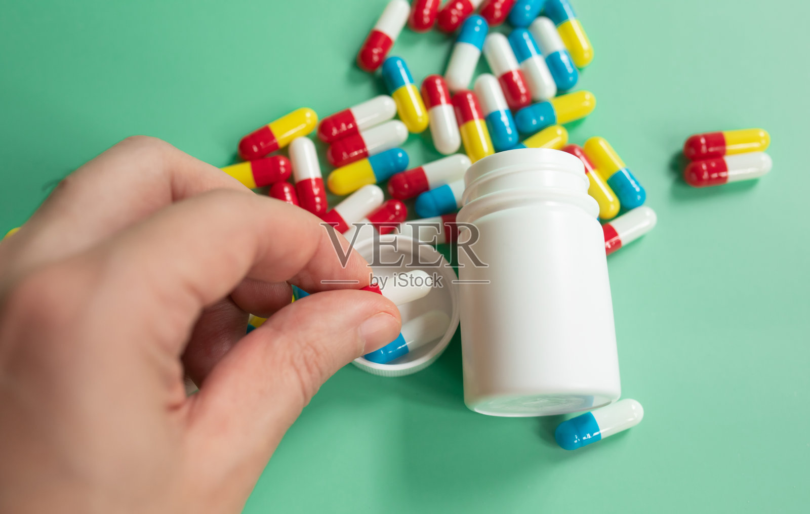 一个男人手里拿着药片、药物或补品，绿色背景的特写。照片摄影图片