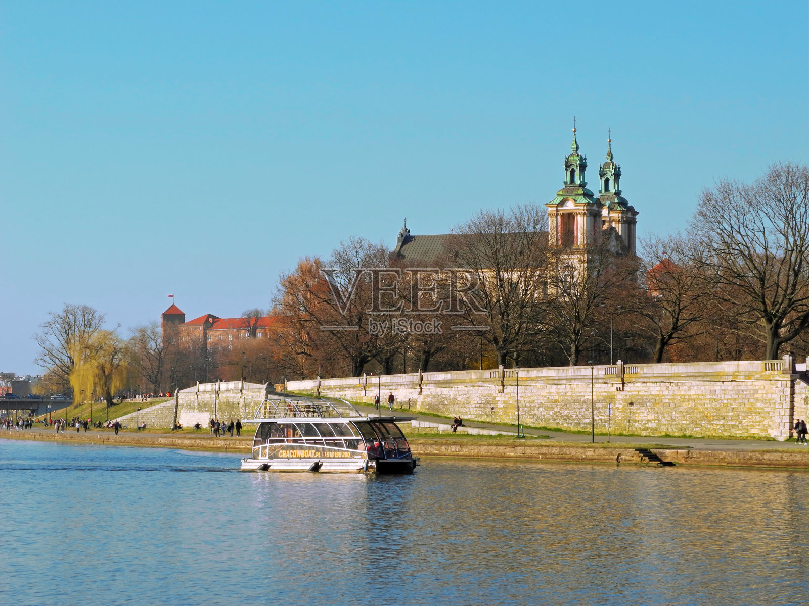 从克拉科夫维斯瓦河的另一岸观赏斯加尔卡天主教教堂、河堤和游船照片摄影图片