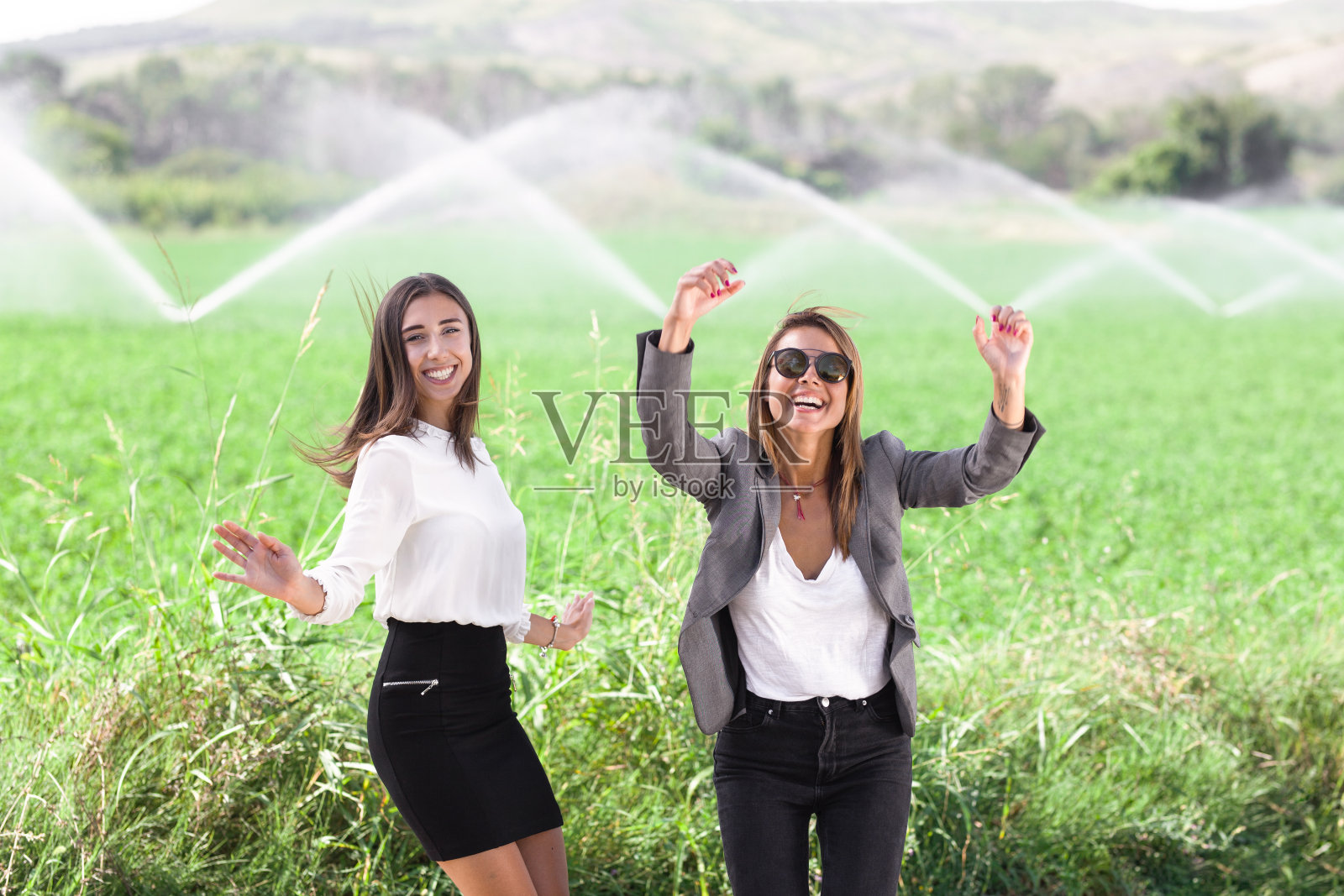 两个女商人在田野里跳跃照片摄影图片