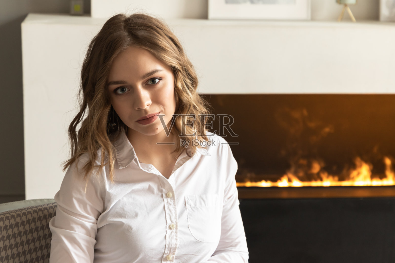 年轻的金发美女坐在壁炉旁照片摄影图片