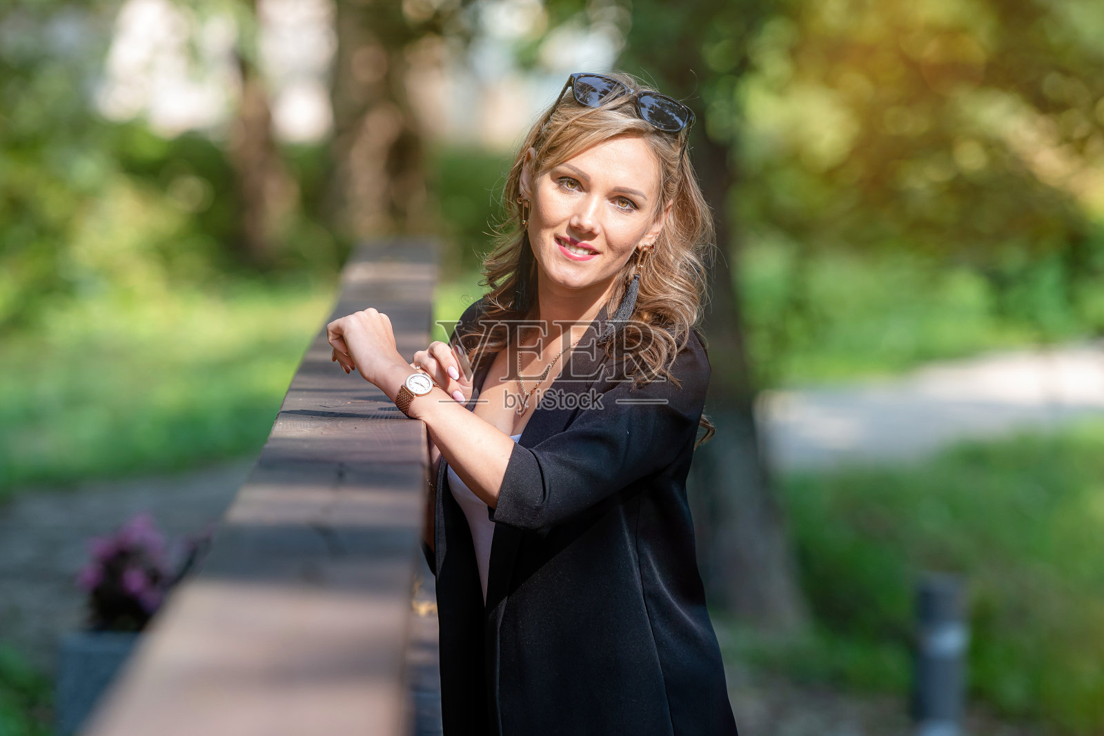 时尚肖像一个时髦漂亮的金发女性戴着太阳镜倚靠在人行桥的栏杆上照片摄影图片