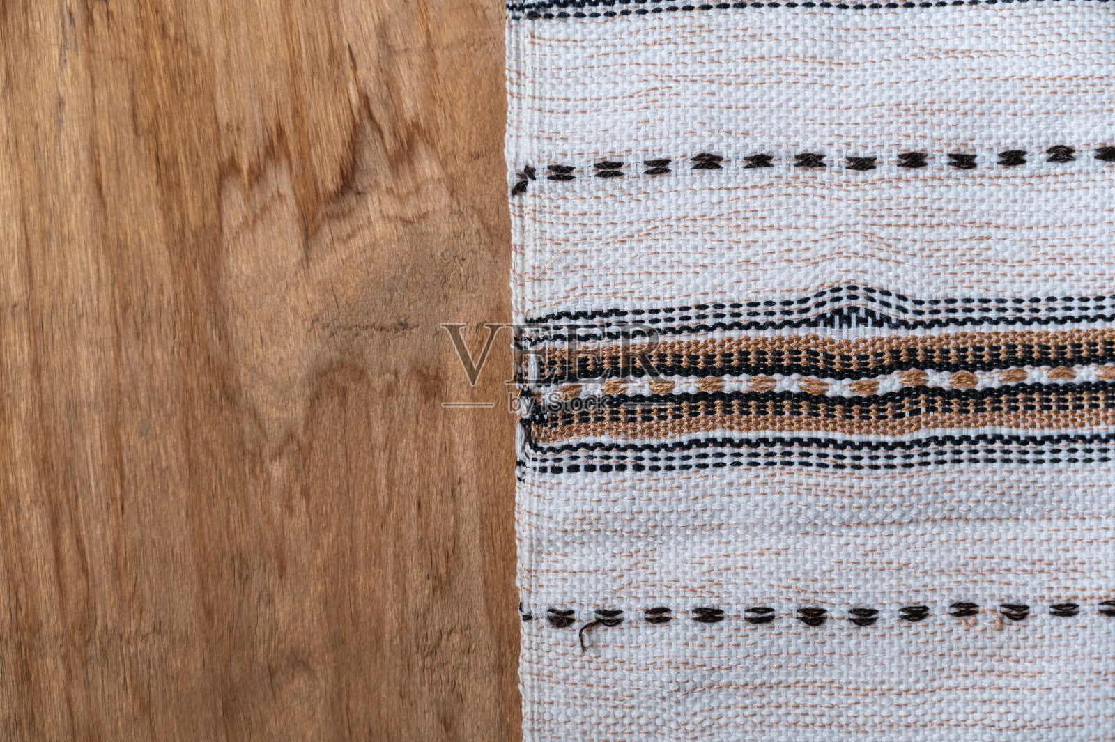 木桌的台面上放着一条白色的厨房毛巾。带流苏的毛巾在粗糙的木板上有流苏和图案。前视图。本空间照片摄影图片