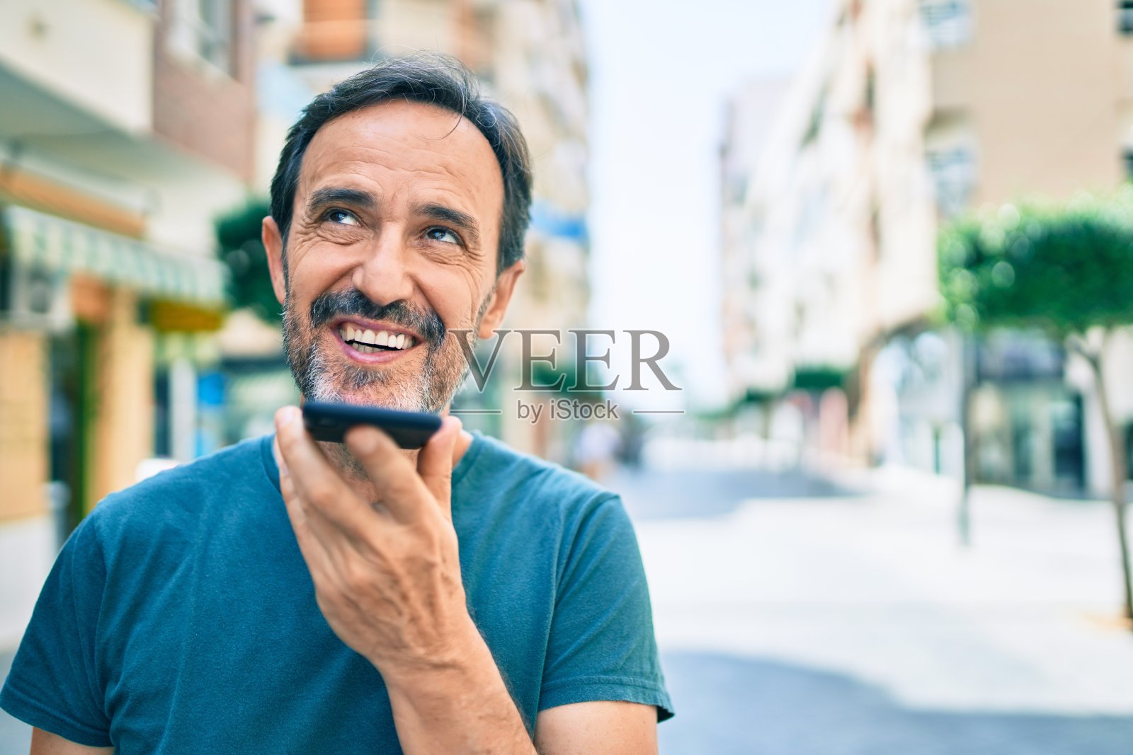 留着胡子的中年男子在户外愉快地微笑着发语音信息照片摄影图片
