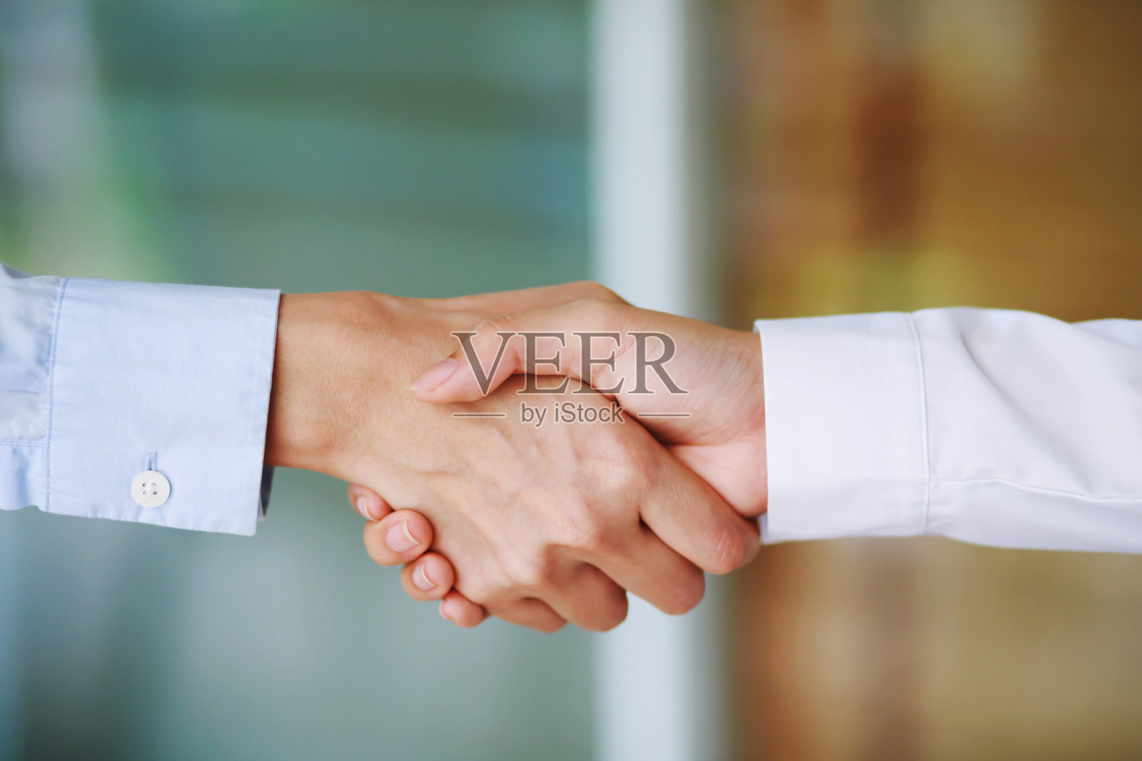 两个同事在工作中握手的特写，格子衬衫照片摄影图片