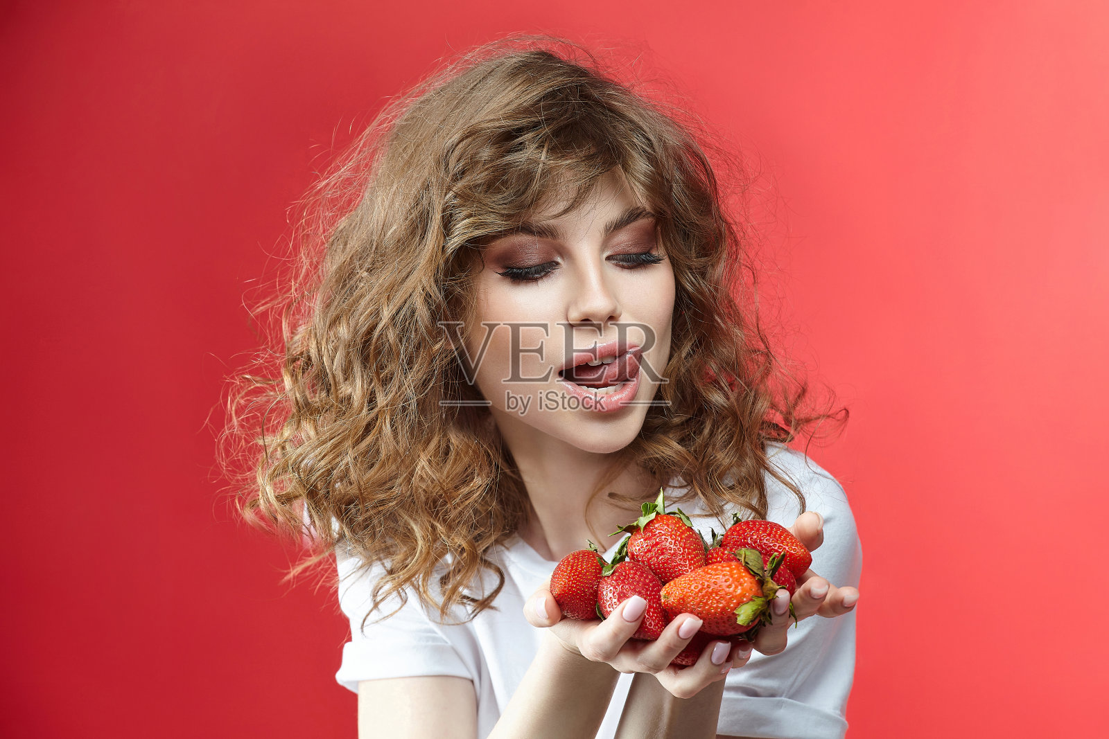 迷人的女孩微笑着，手里拿着一把草莓。照片摄影图片
