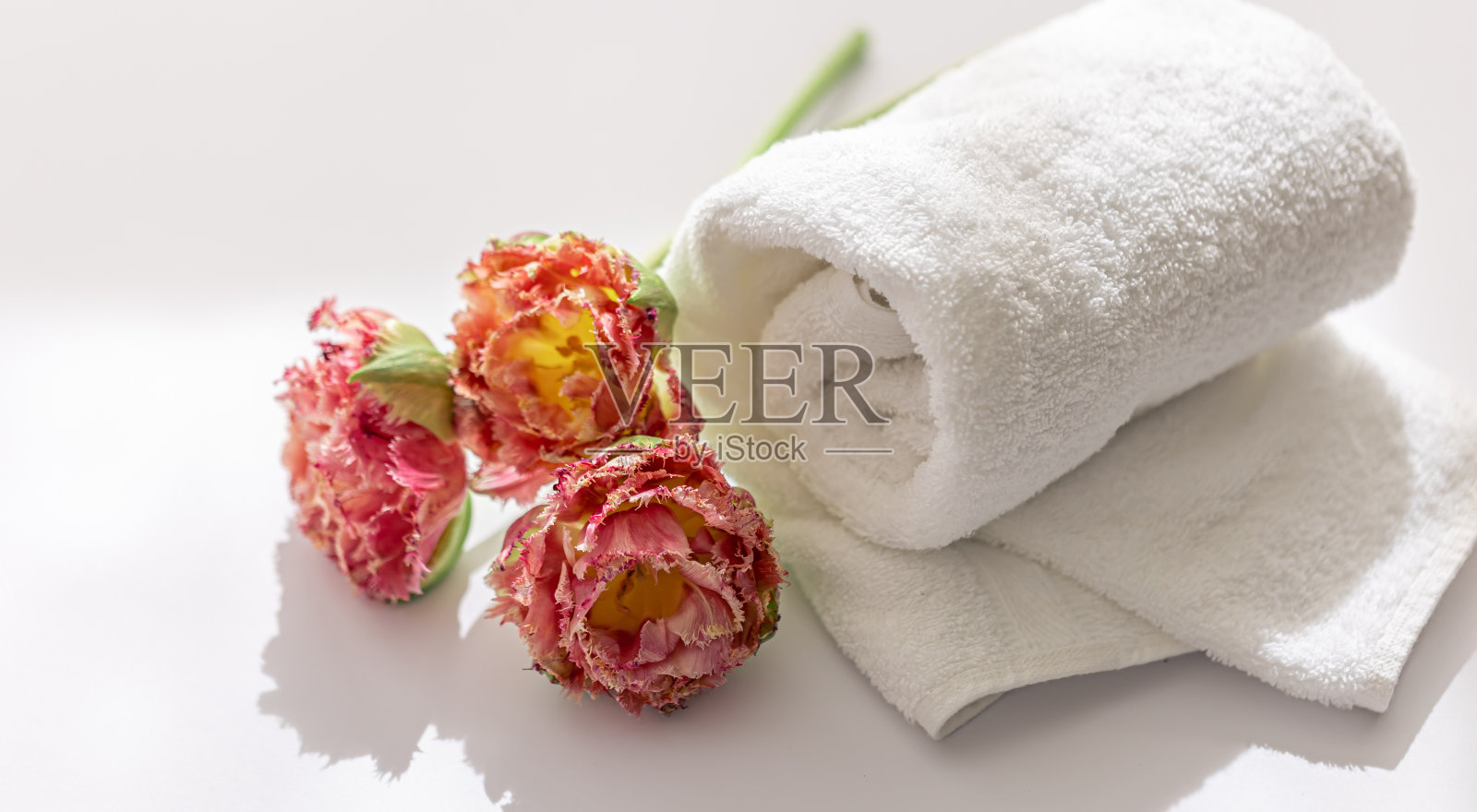特写镜头，白色毛巾布浴巾和鲜花。照片摄影图片