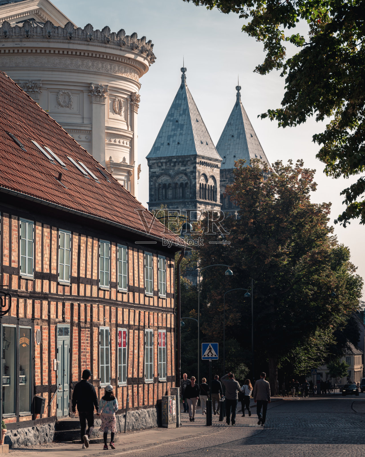 瑞典隆德——2020年9月19日:人们走在与隆德大教堂等历史建筑接壤的鹅卵石街道上照片摄影图片