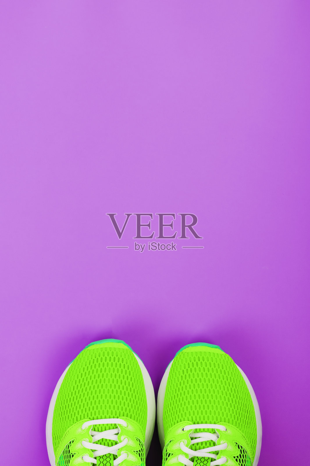 紫色背景上的绿色跑鞋。照片摄影图片
