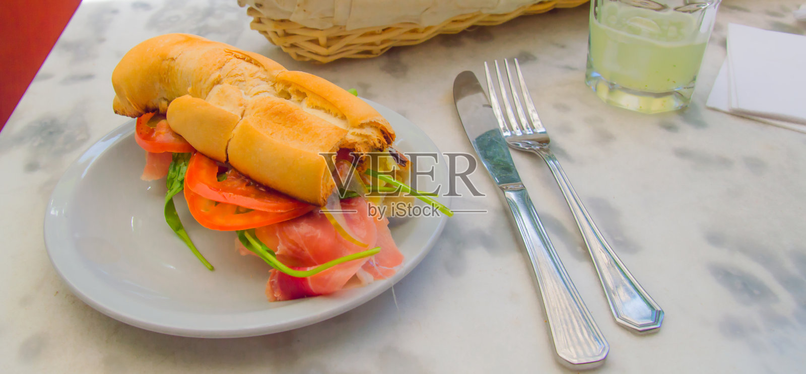 户外餐桌，生火腿和芝麻菜三明治配天然果汁照片摄影图片