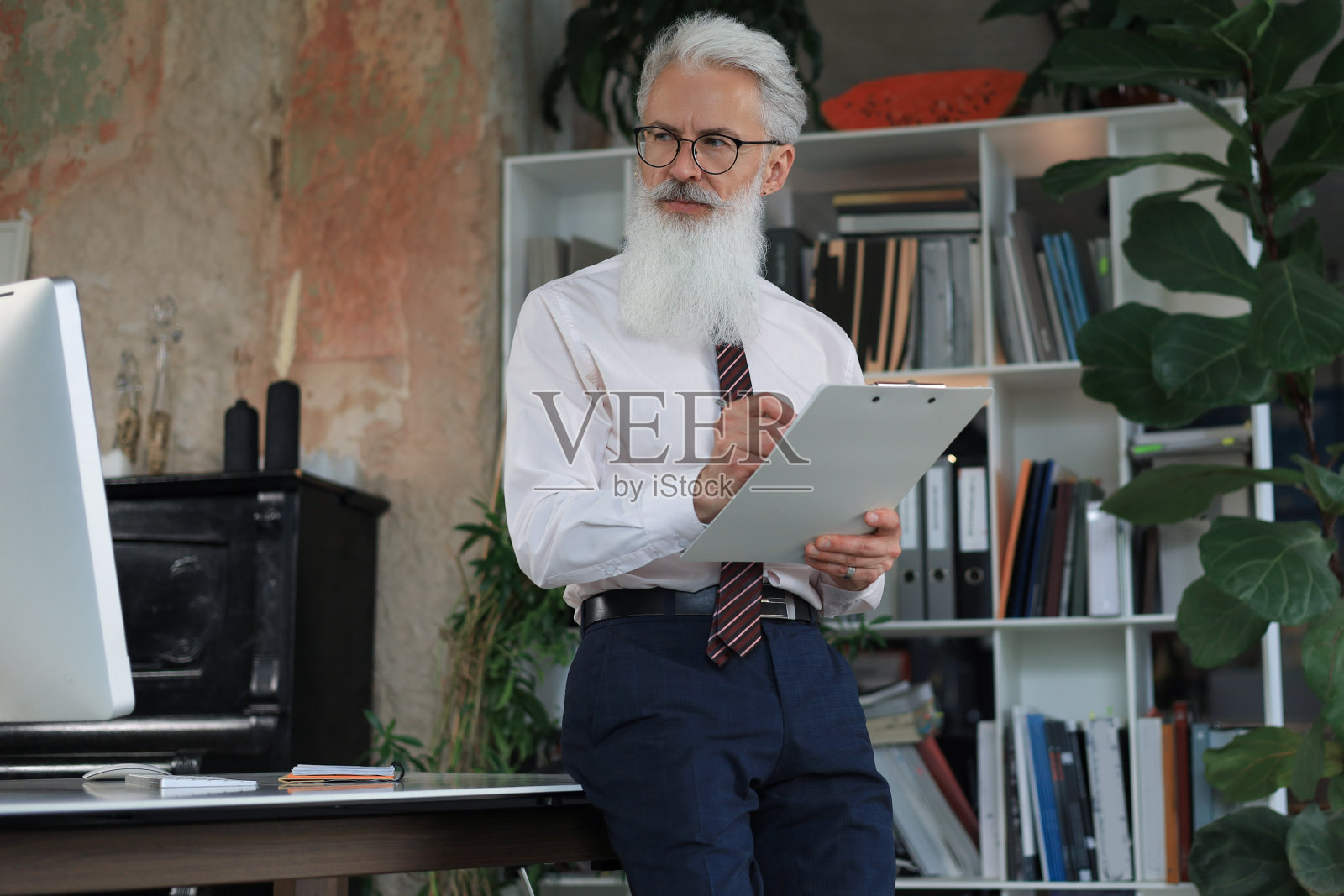 专注的成熟商人在他现代化的办公室里工作和做笔记。照片摄影图片