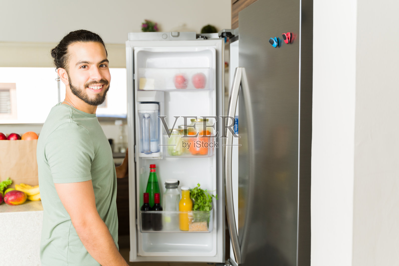 一个兴高采烈的年轻人在厨房里找冰箱里的食物照片摄影图片