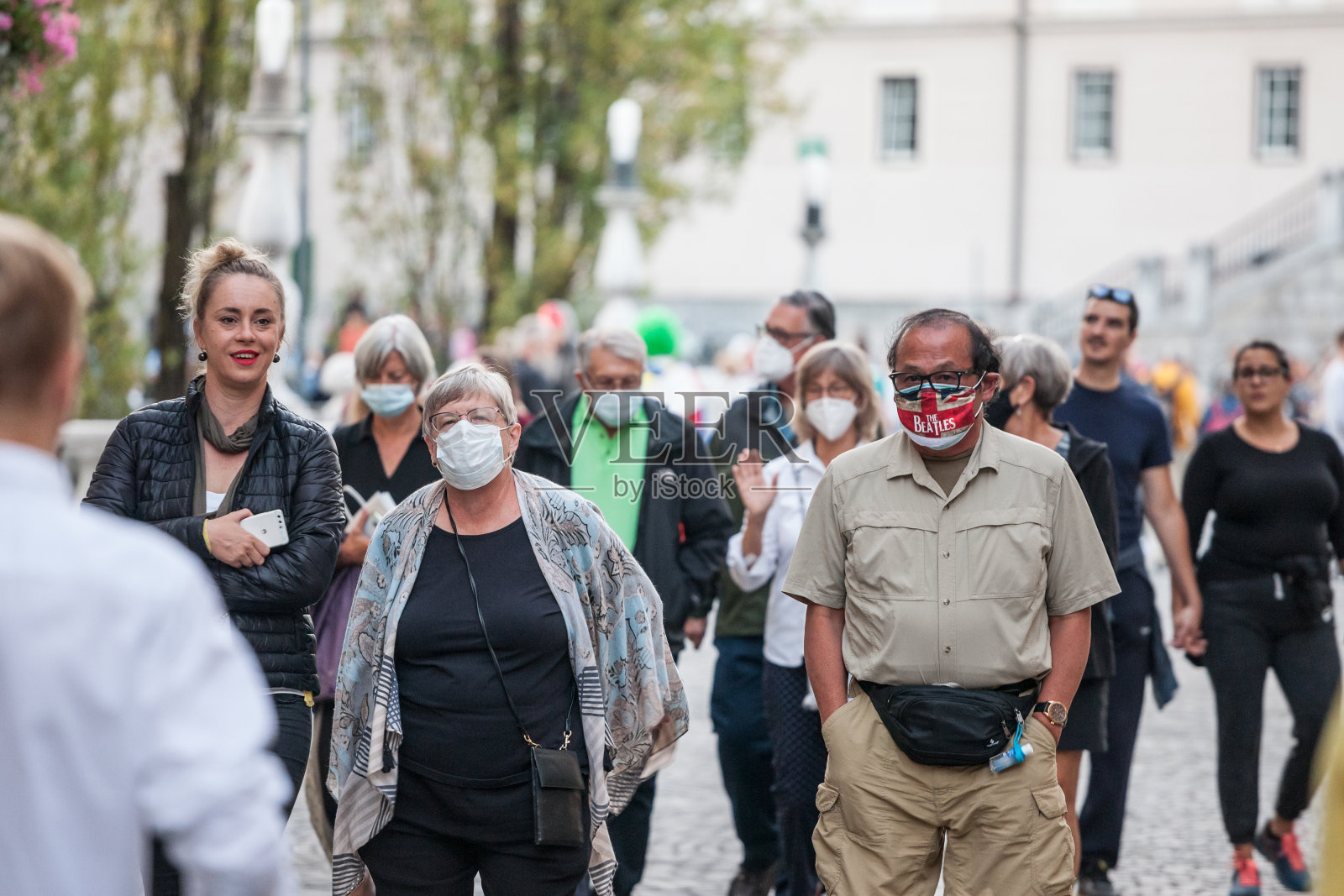 新冠肺炎危机期间，一名戴着口罩的老年男子和女子在卢布尔雅那拥挤的街道上醒来。照片摄影图片