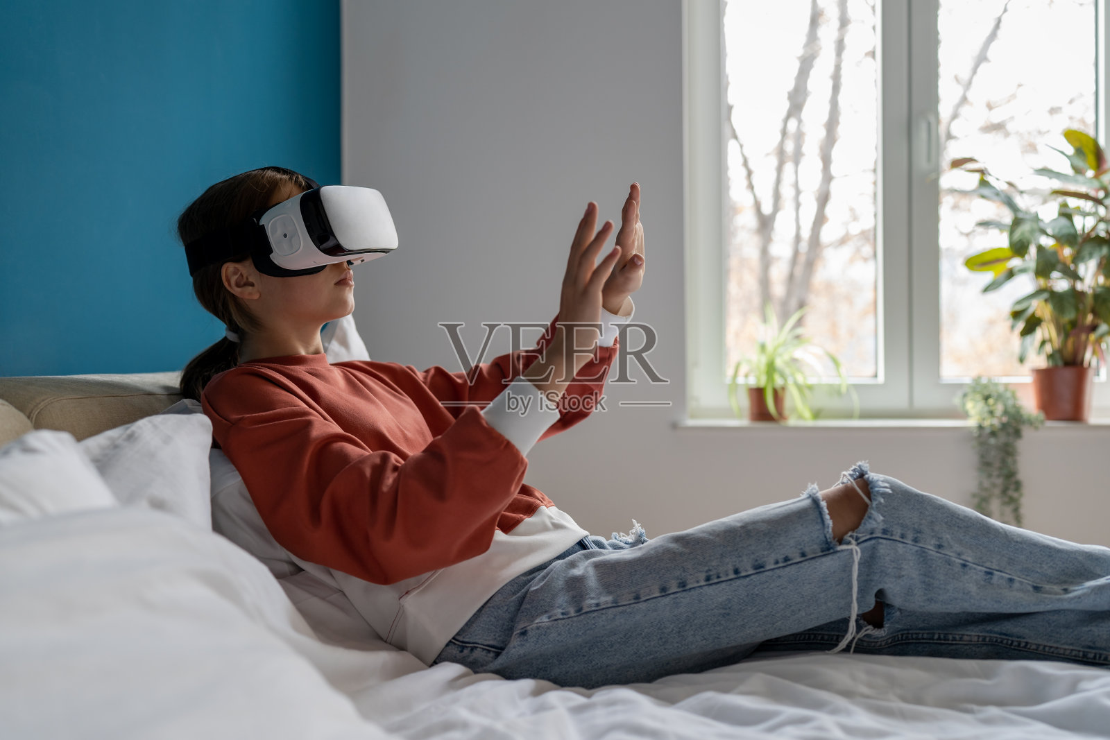 十几岁的女孩在家里休息时戴着现代虚拟现实眼镜，触摸着虚拟世界中的东西照片摄影图片