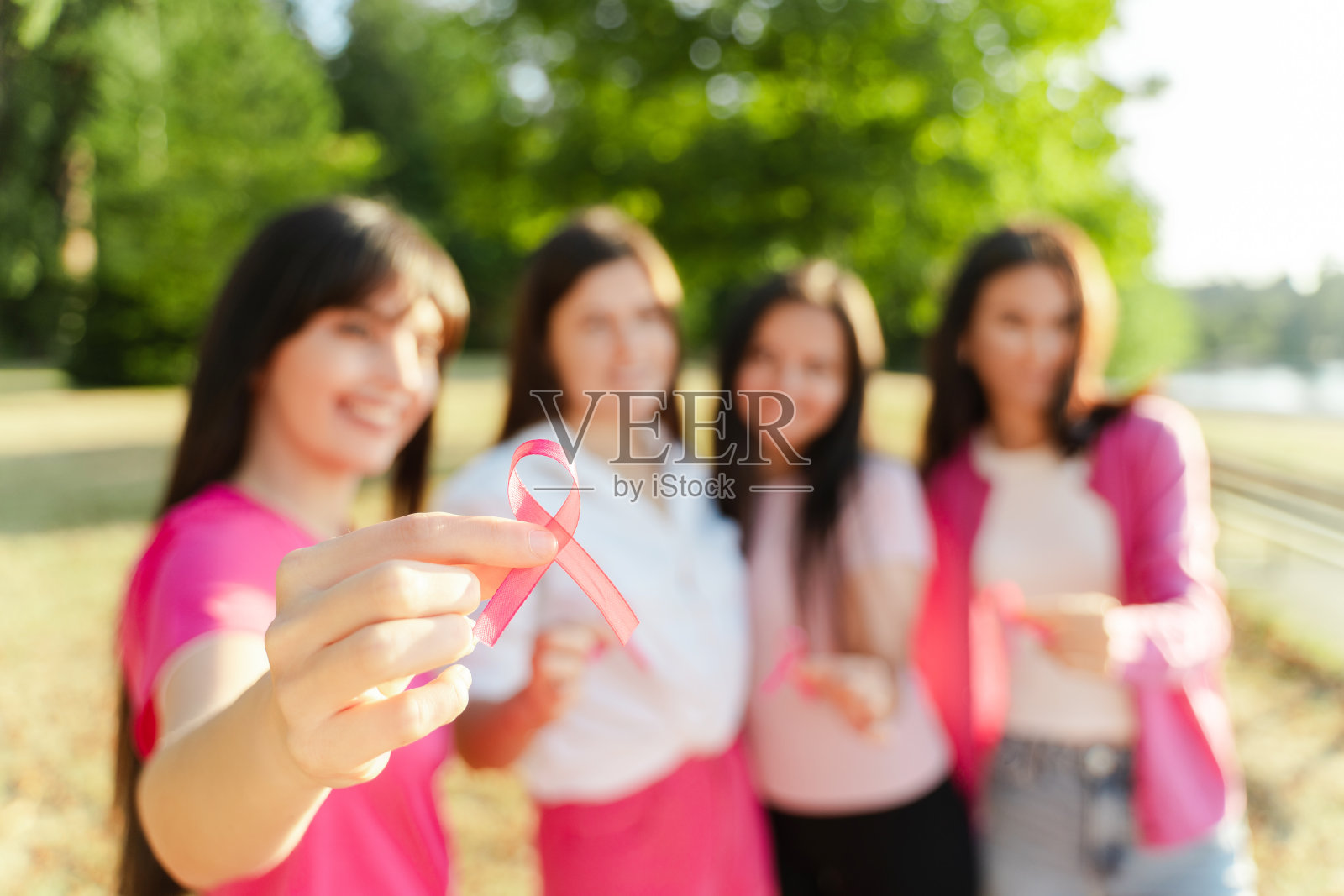 四个微笑自信的中年妇女手持粉色丝带，看着镜头照片摄影图片