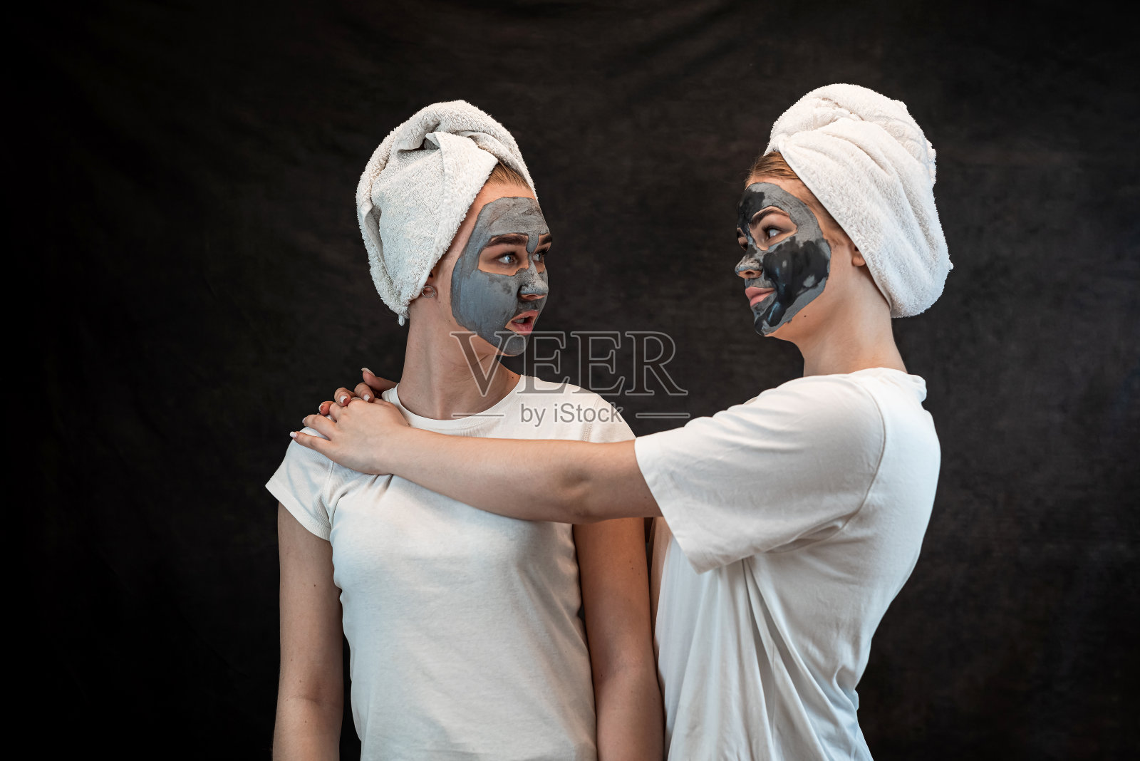 阳性白种人妇女穿着白色毛巾玩黑粘土或泥面膜隔离照片摄影图片