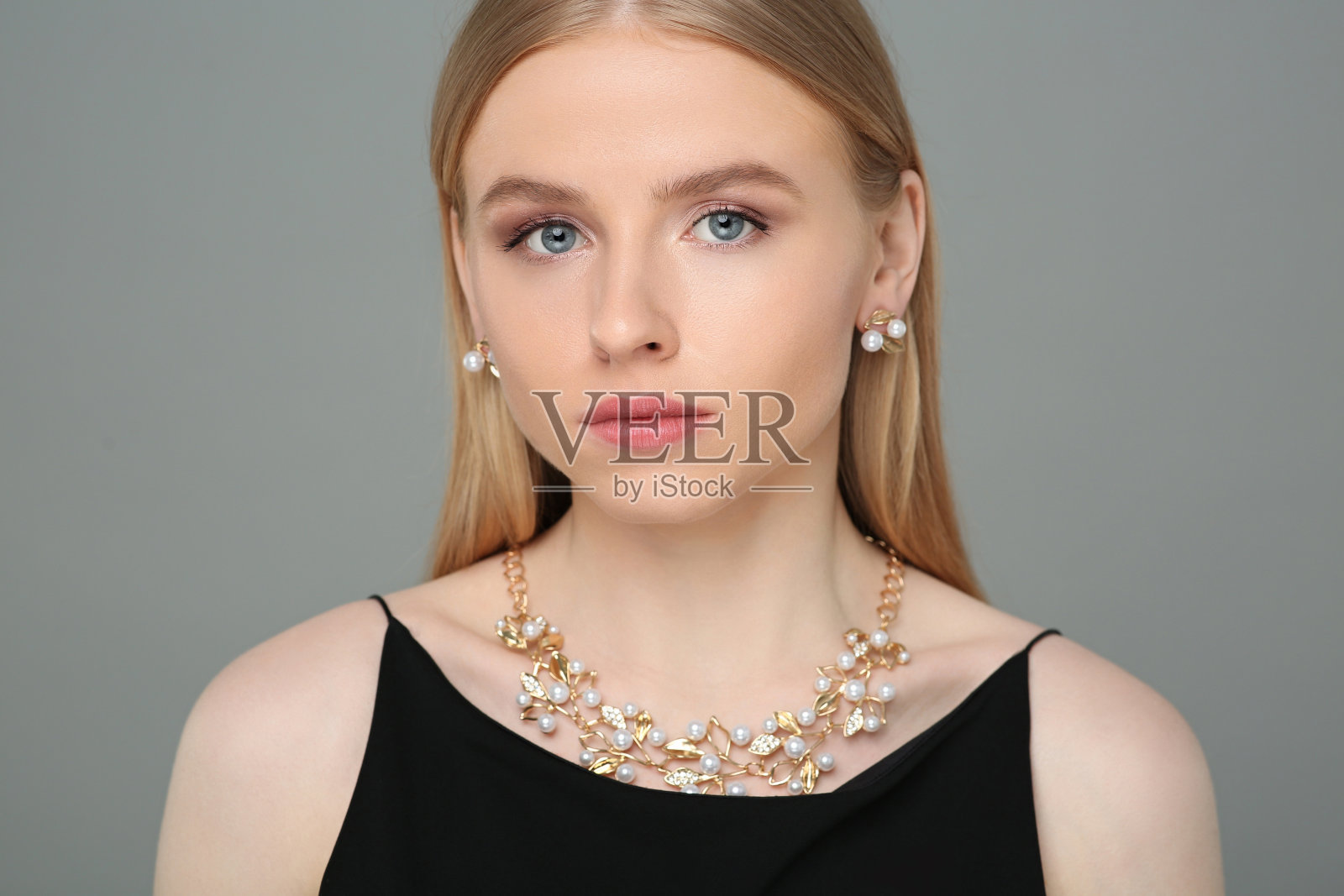 美丽的年轻女子与优雅的珠宝在灰色的背景照片摄影图片