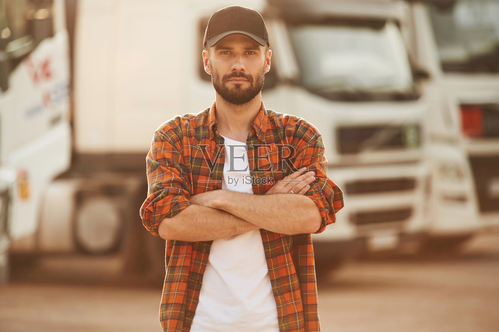 双臂交叉，站着。穿着便服的年轻卡车司机照片摄影图片