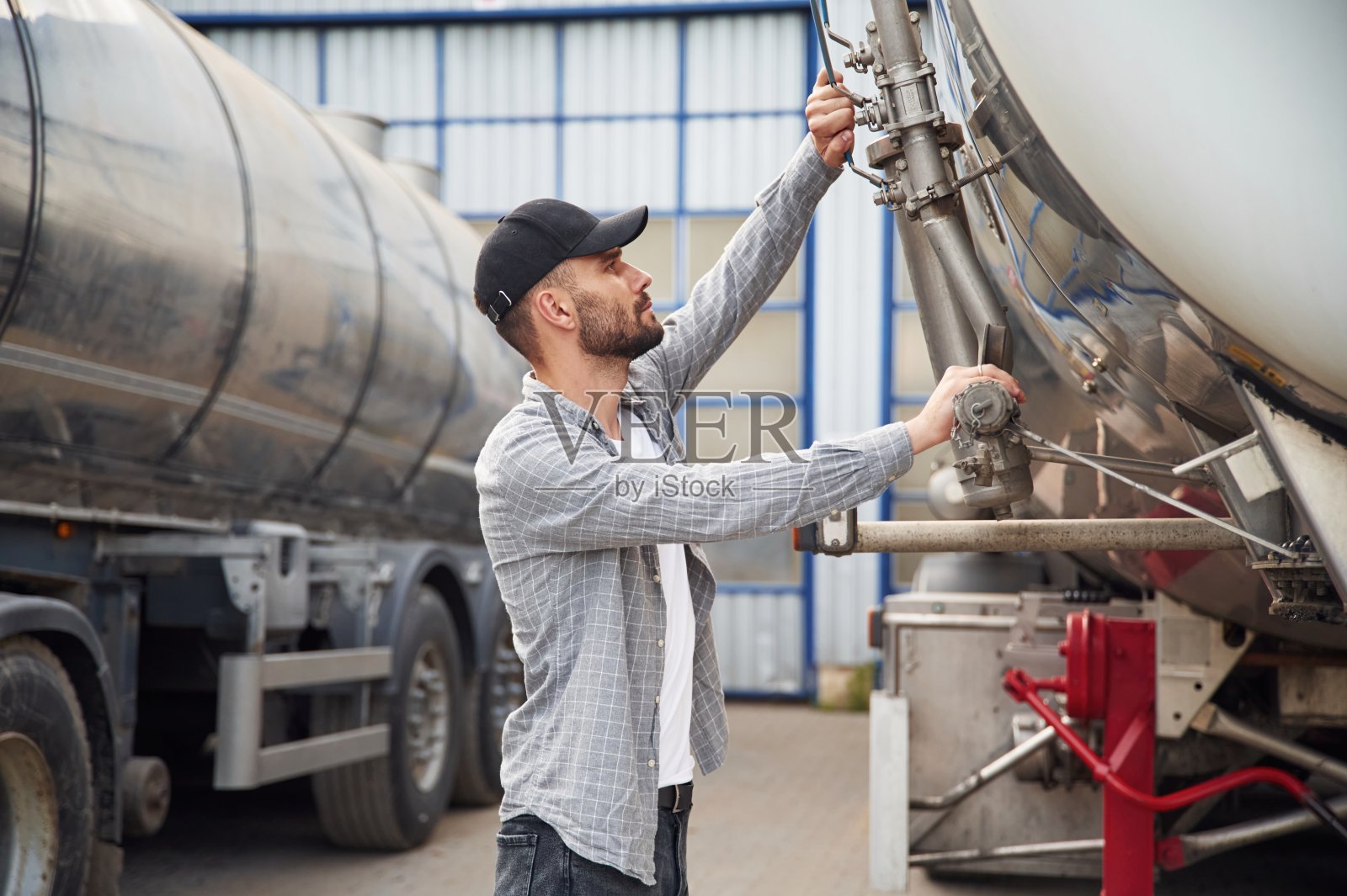 在两辆车之间。穿着便服的年轻卡车司机照片摄影图片