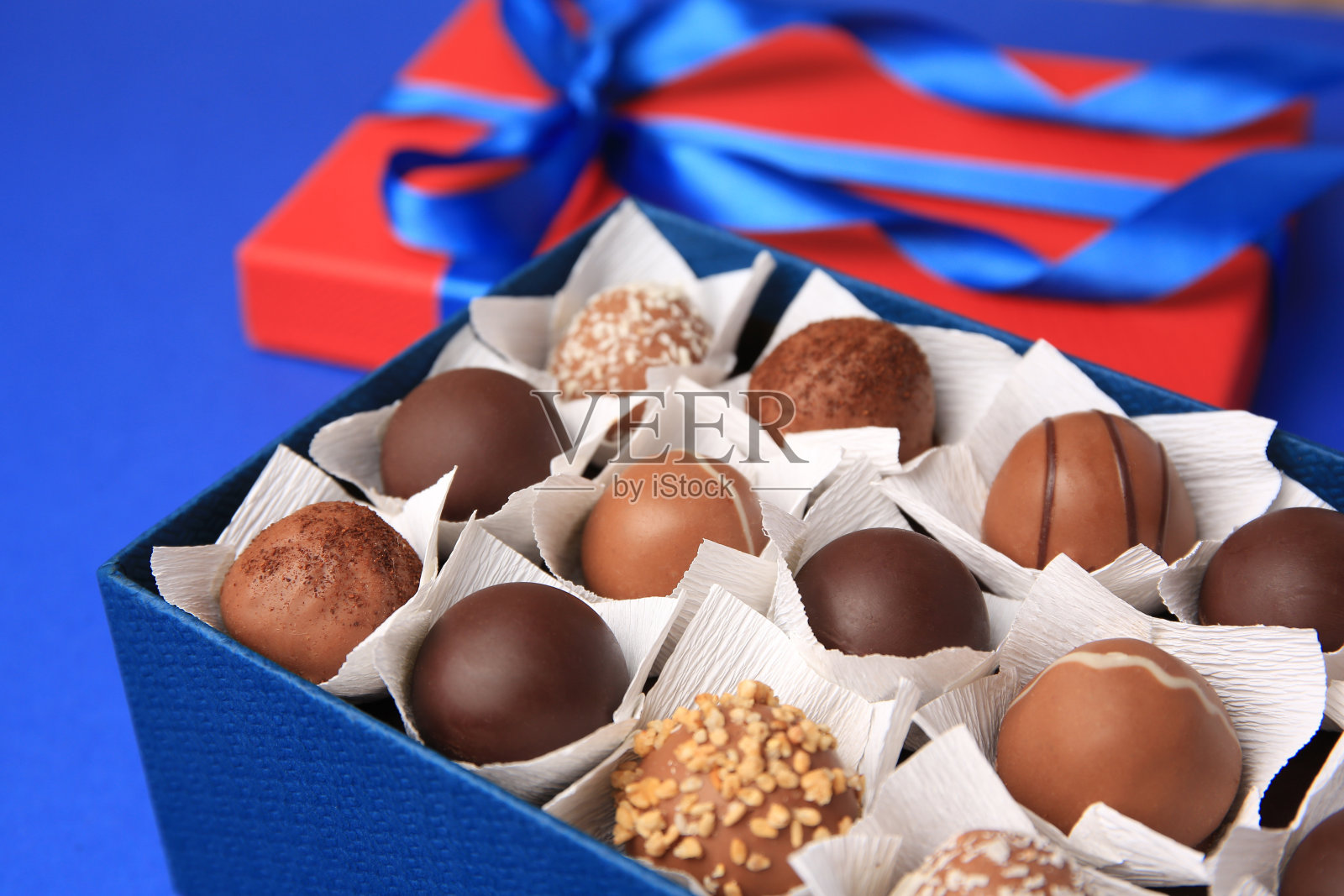 盒子与美味的巧克力糖果在蓝色背景，特写照片摄影图片