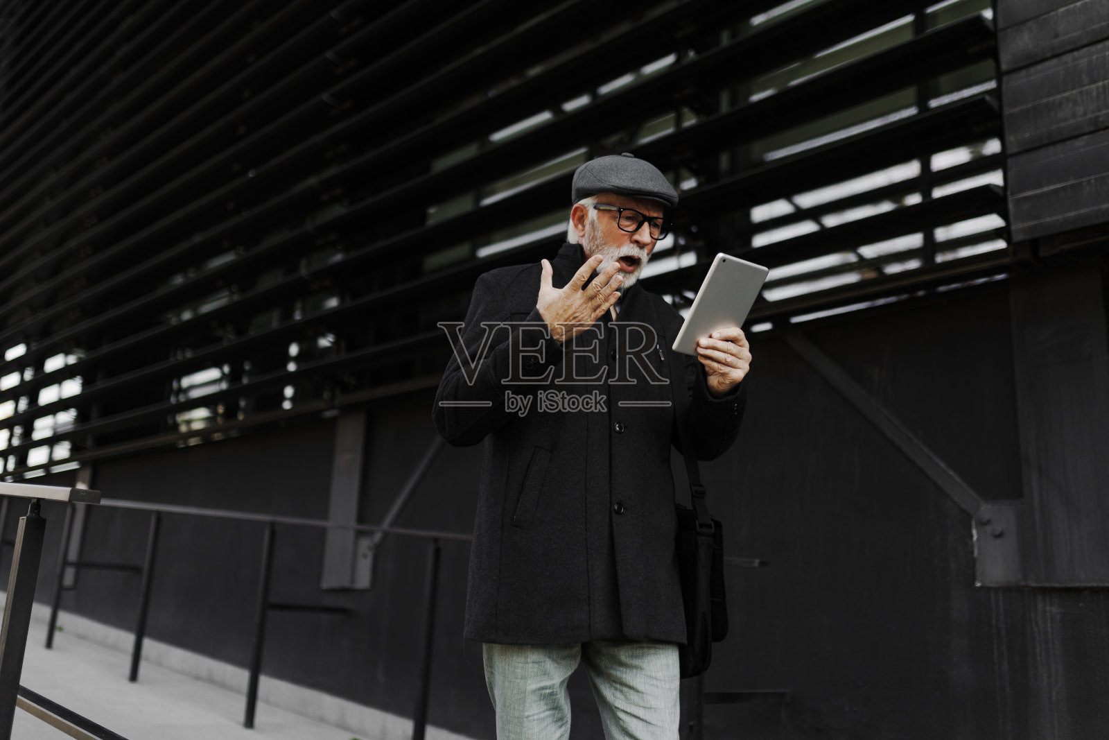愤怒的商人在户外使用数码平板电脑照片摄影图片