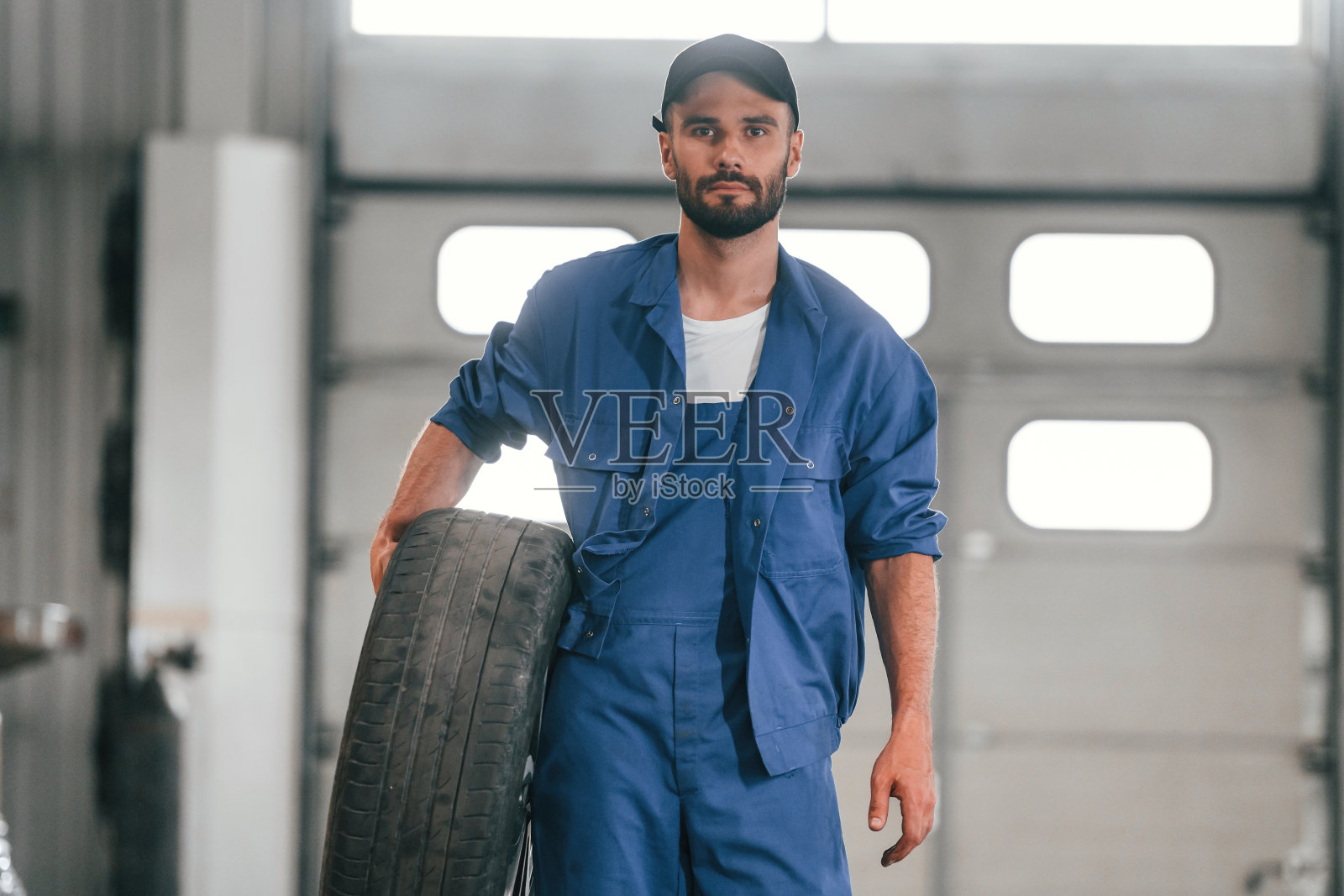 轮胎在手。汽车修理工在汽车修理厂工作。维修服务照片摄影图片