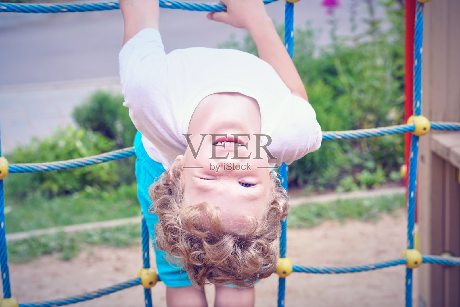 一个小孩子在操场上玩设备玩得很开心。照片摄影图片