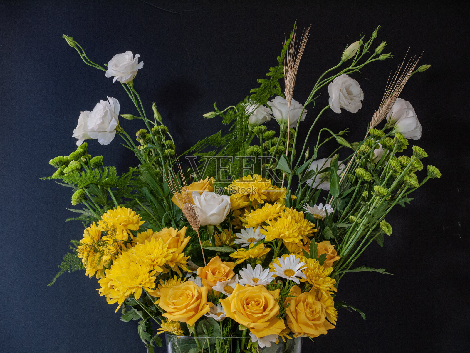 花束，玫瑰，雏菊和绿色的花和穗在一个花瓶在黑色的背景。照片摄影图片