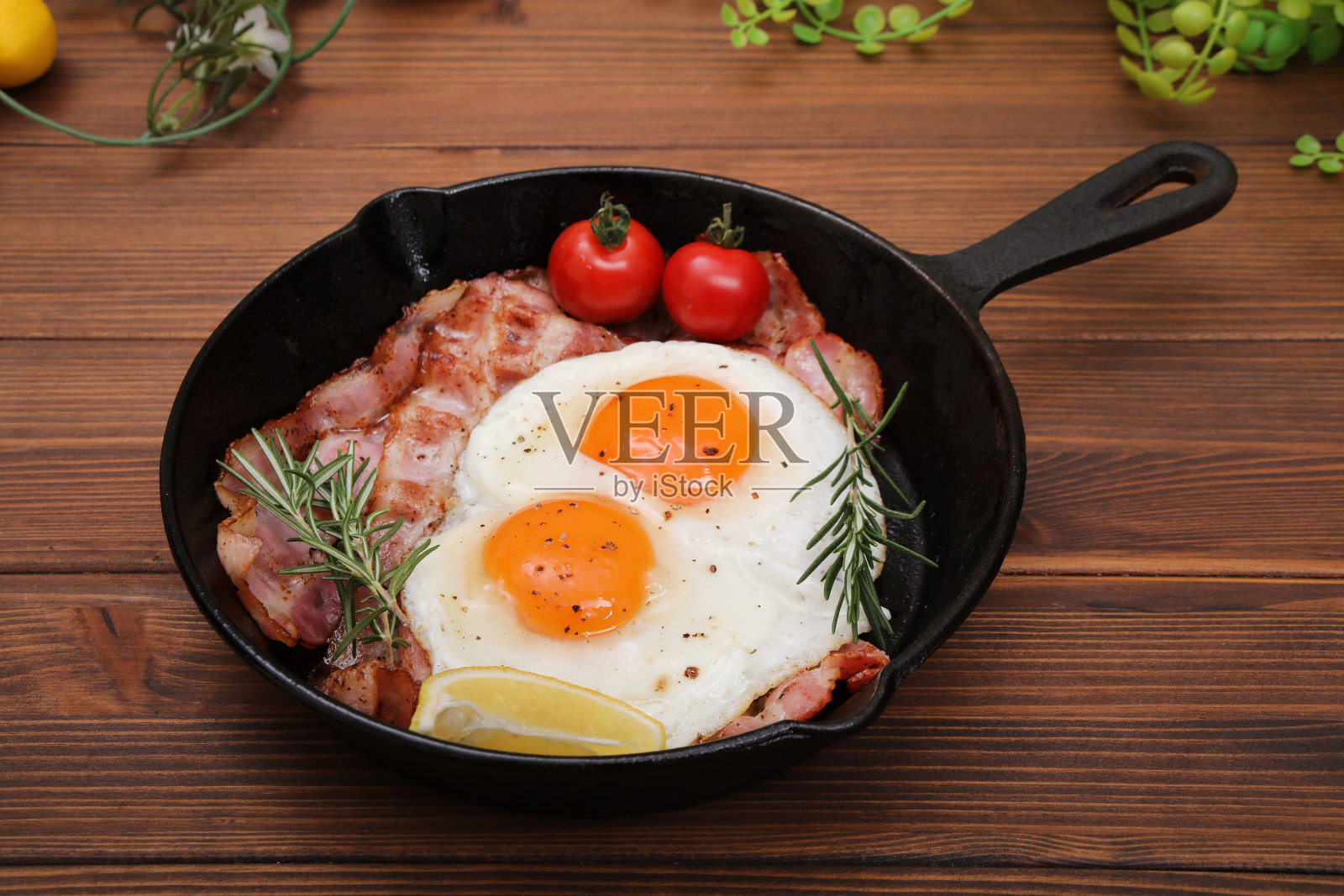 在木桌上的煎锅里煎鸡蛋和熏肉照片摄影图片