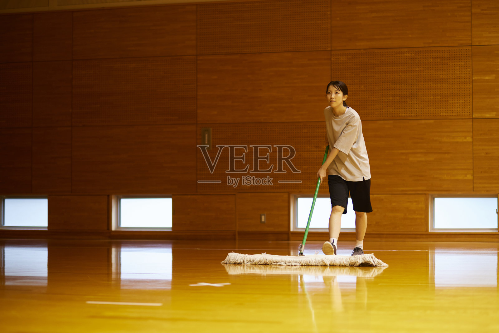 日本妇女用拖把打扫体育馆照片摄影图片