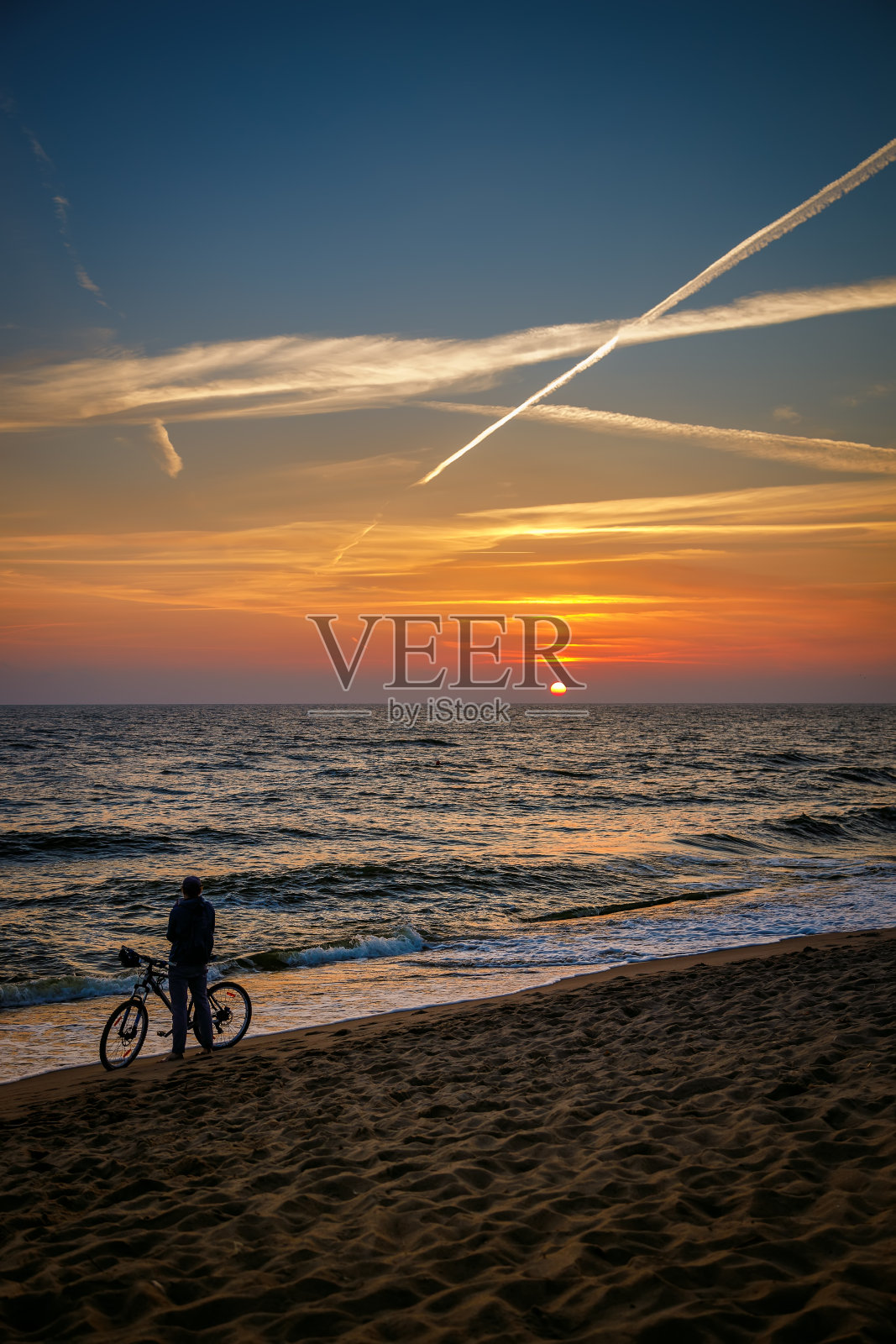 一个骑自行车的人欣赏着海边令人惊叹的日落照片摄影图片