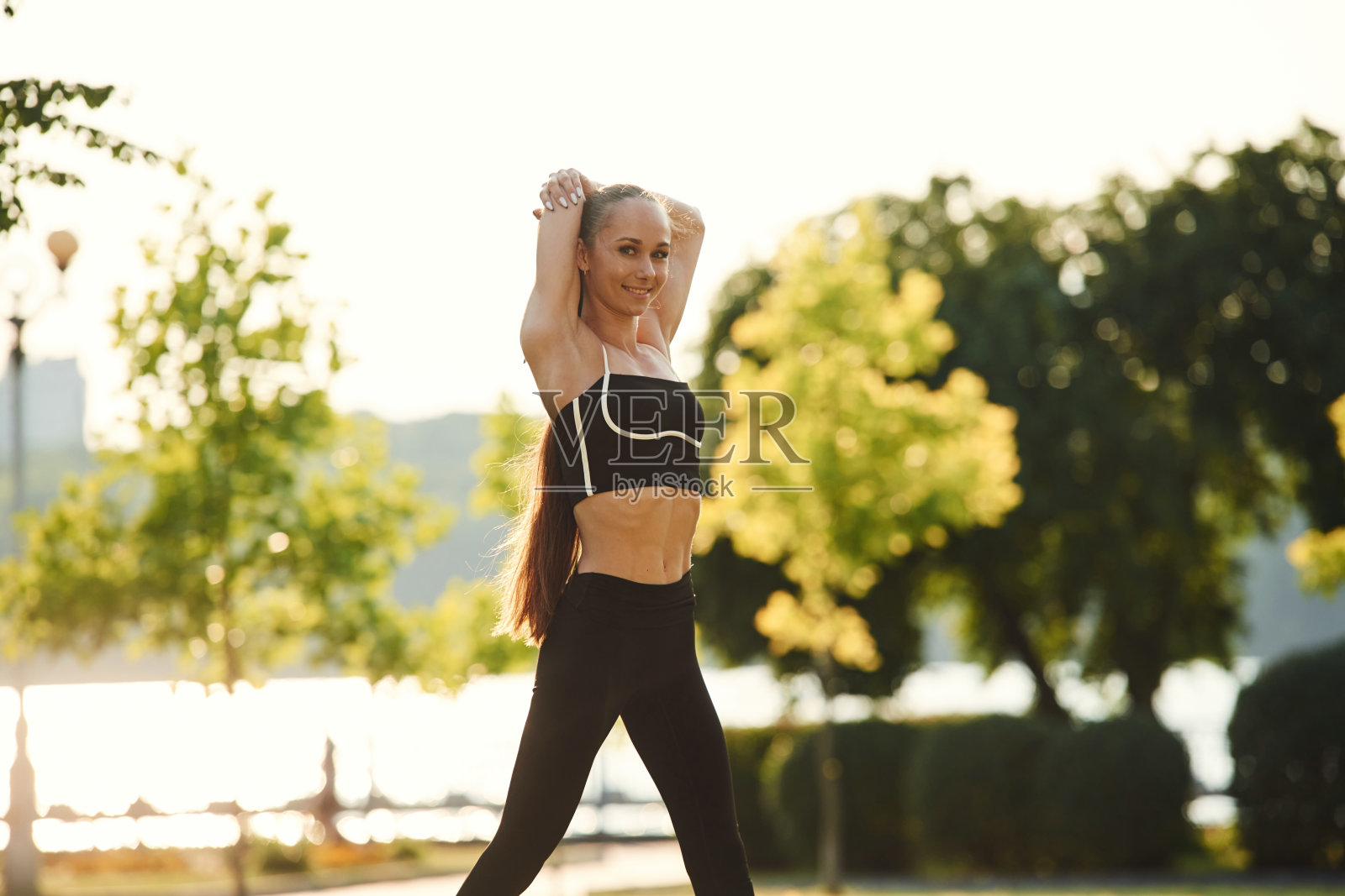 为健身做准备。阳光明媚的白天，穿着运动服的漂亮年轻女子在公园里照片摄影图片