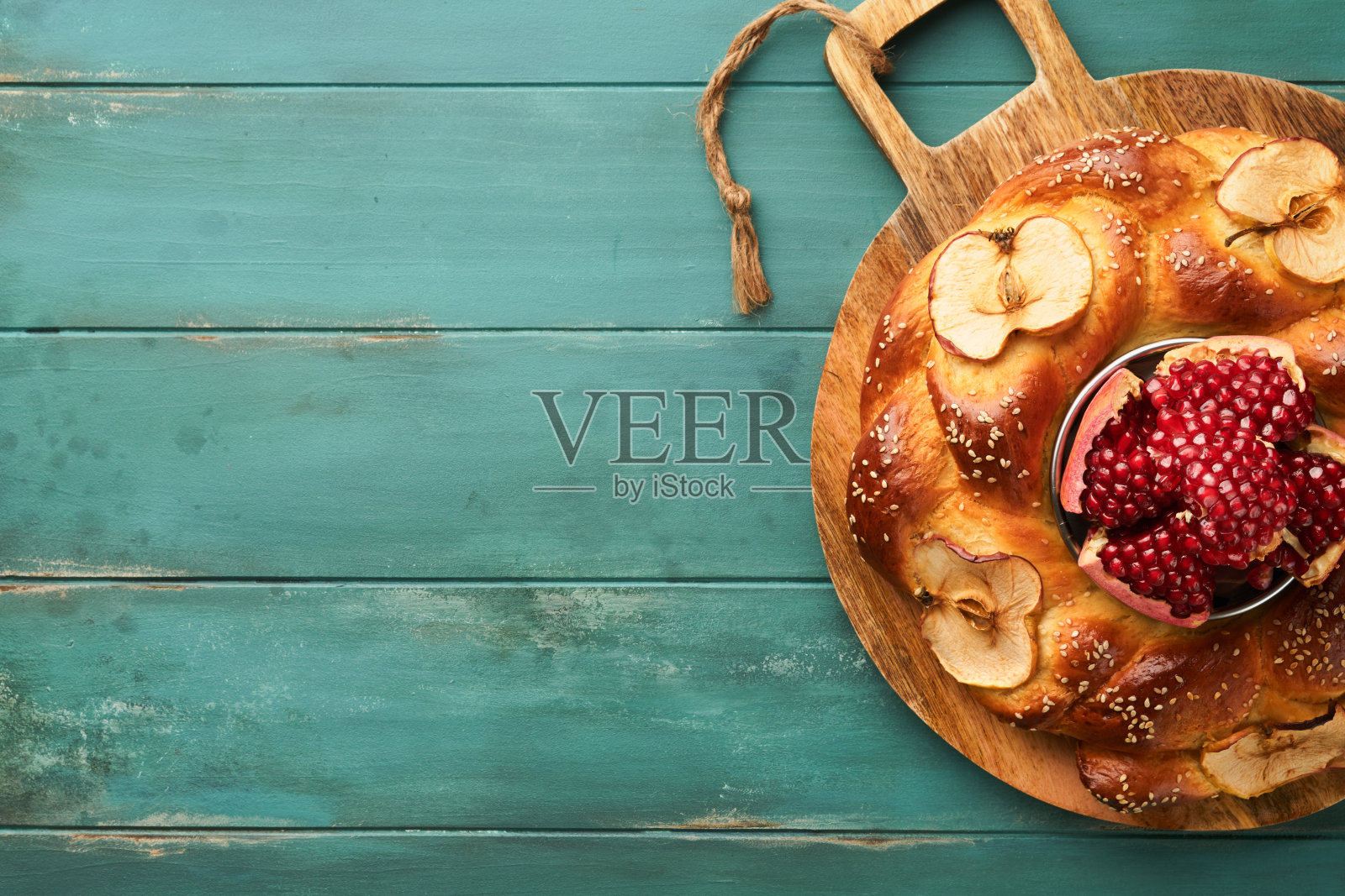 犹太节日-犹太新年或犹太新年。石榴，苹果，蜂蜜和圆面包在古老的木制蓝色桌子背景。犹太人的秋天庆祝活动。Shana Tova。赎罪日的概念。俯视图照片摄影图片