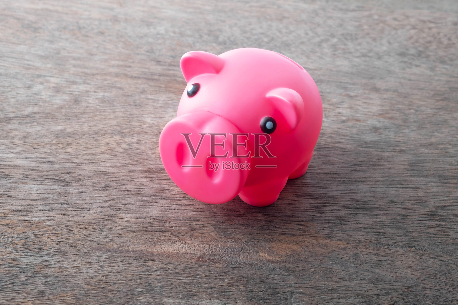 存钱罐，往存钱罐里放一枚硬币，往存钱罐里放一枚硬币，粉色的存钱罐。照片摄影图片